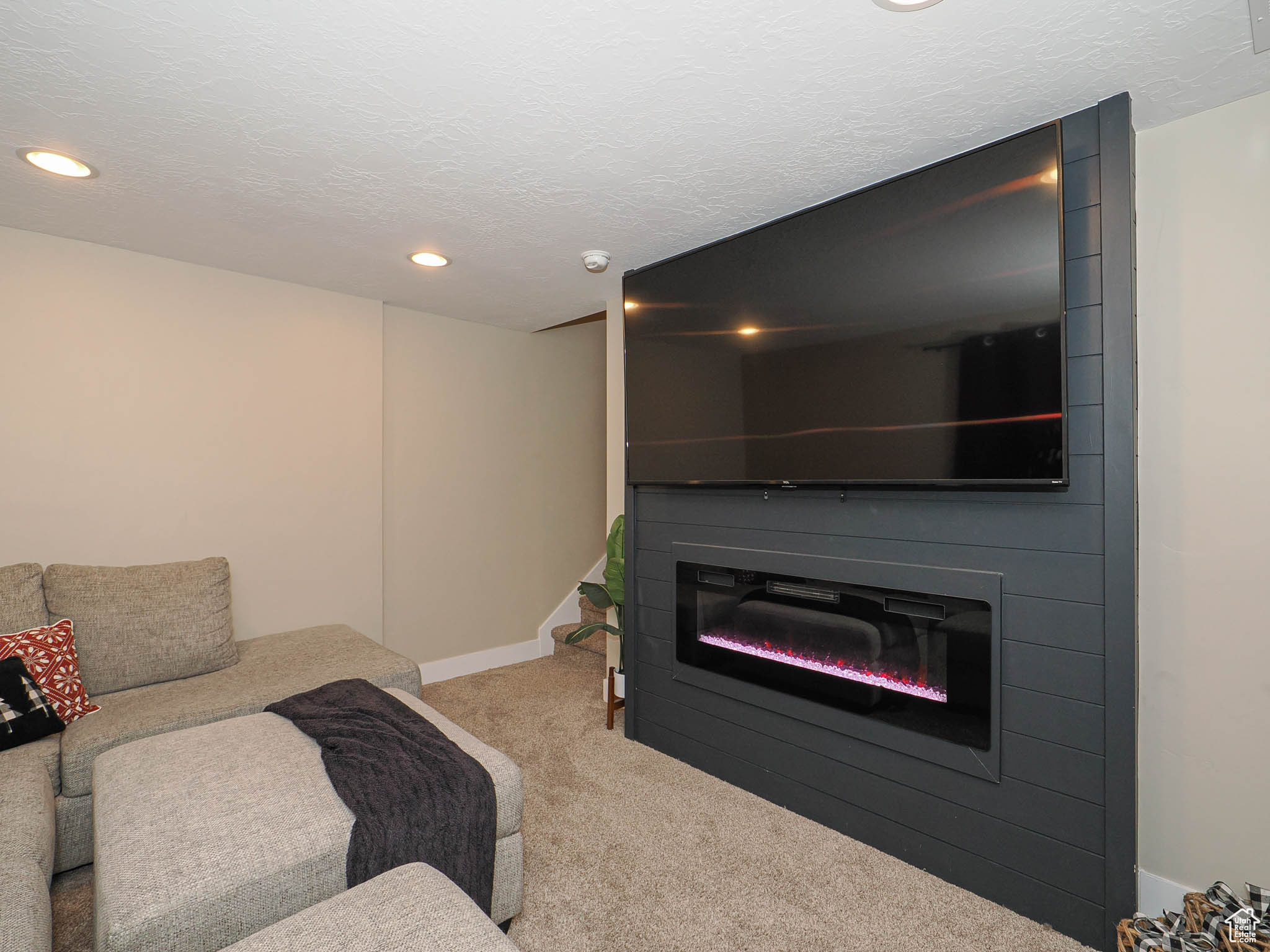 Carpeted living room featuring a large fireplace and a textured ceiling