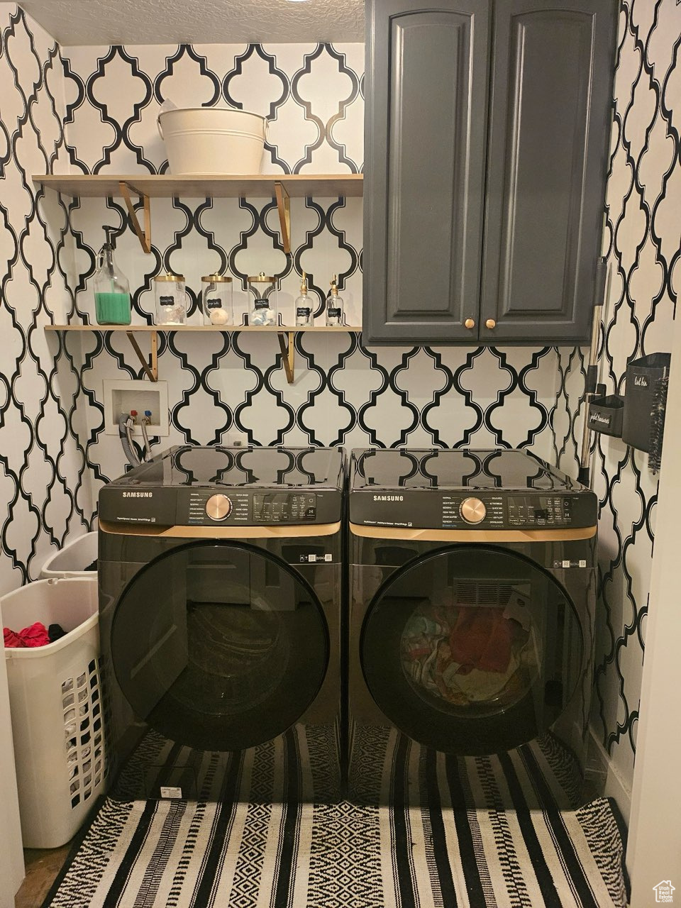 Laundry area featuring cabinets, a textured ceiling, and washing machine and clothes dryer