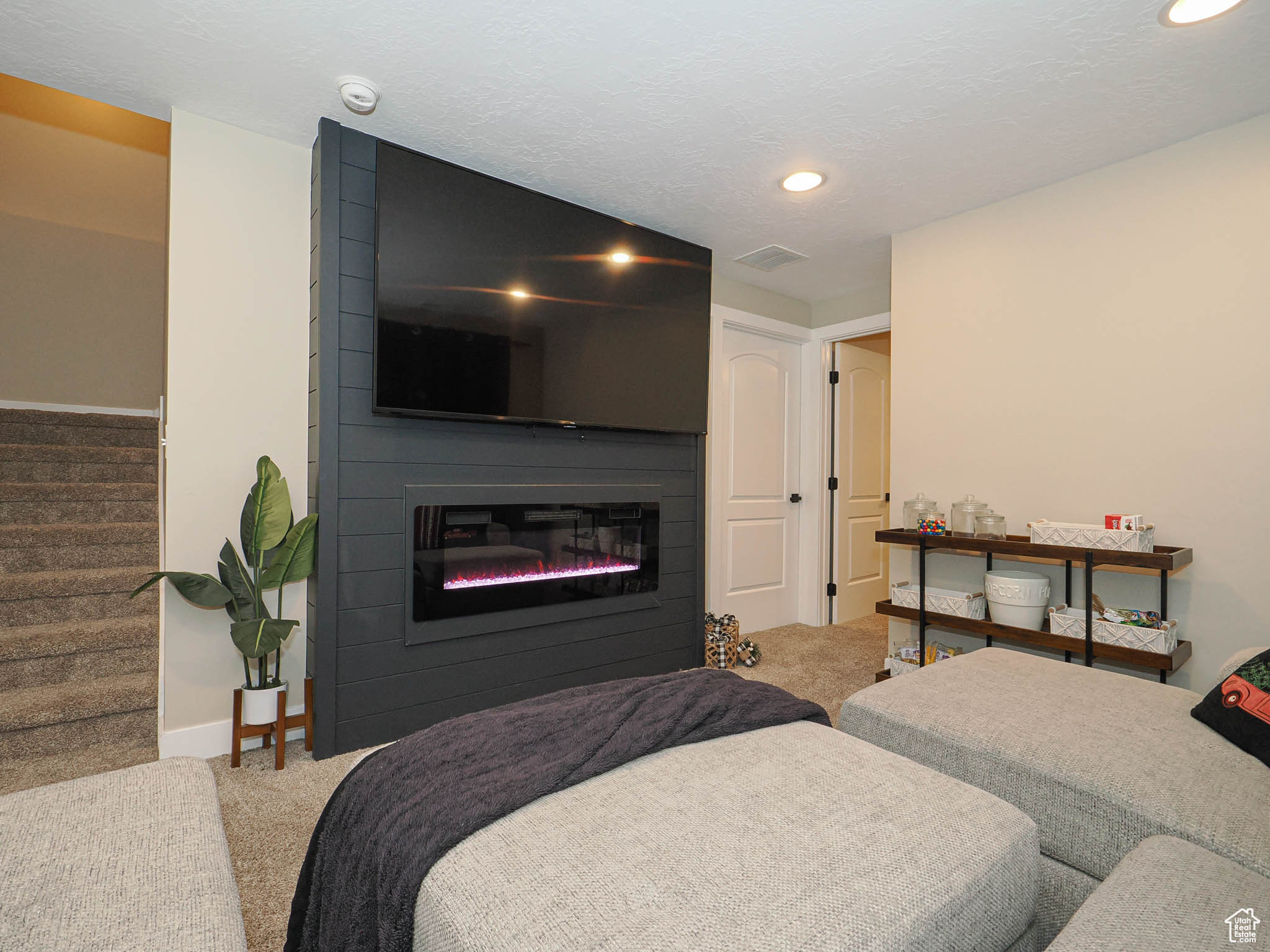 Carpeted living room featuring a textured ceiling and a fireplace