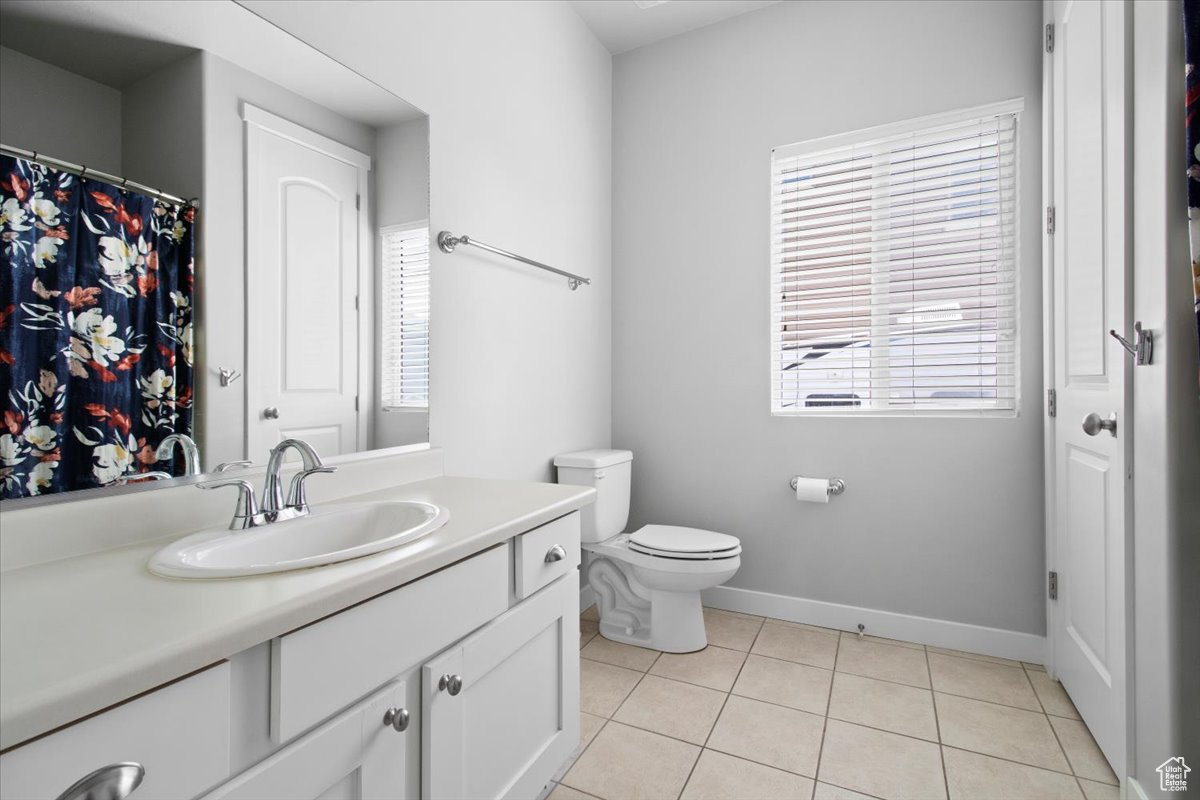 Bathroom featuring tile patterned flooring, vanity, toilet, and a wealth of natural light