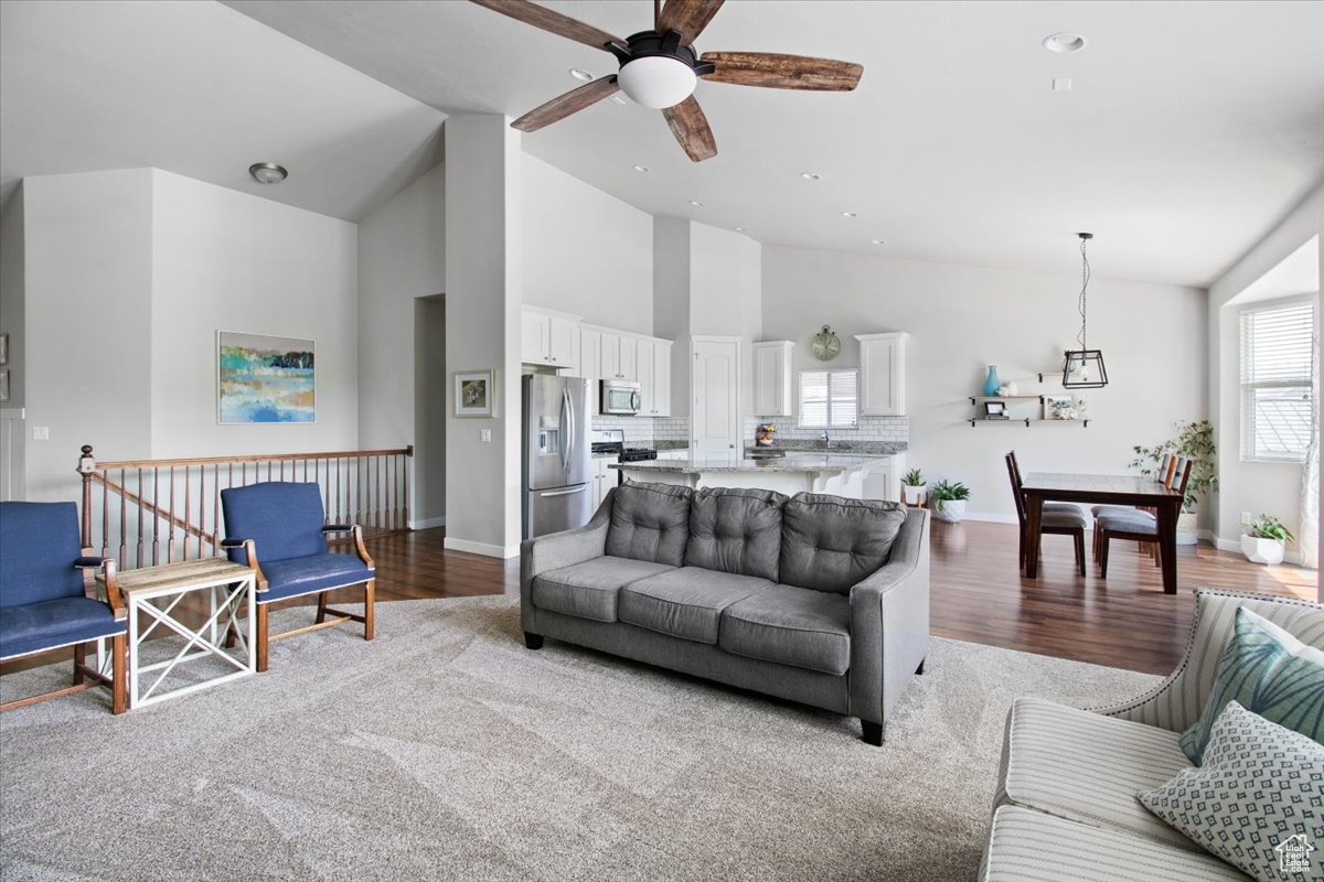 Living room with ceiling fan, high vaulted ceiling, and light hardwood / wood-style floors