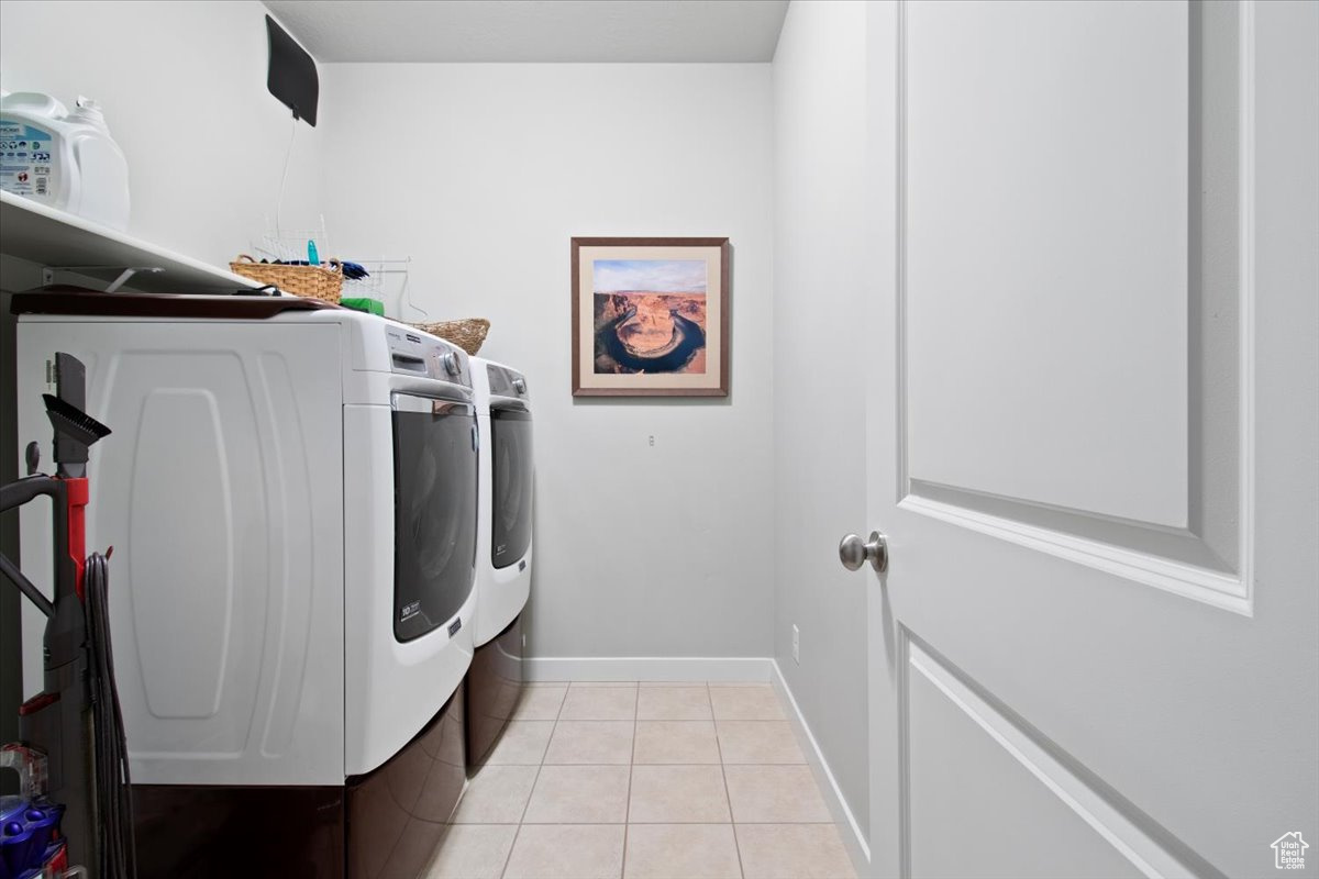 Laundry room featuring light tile patterned floors and washing machine and clothes dryer