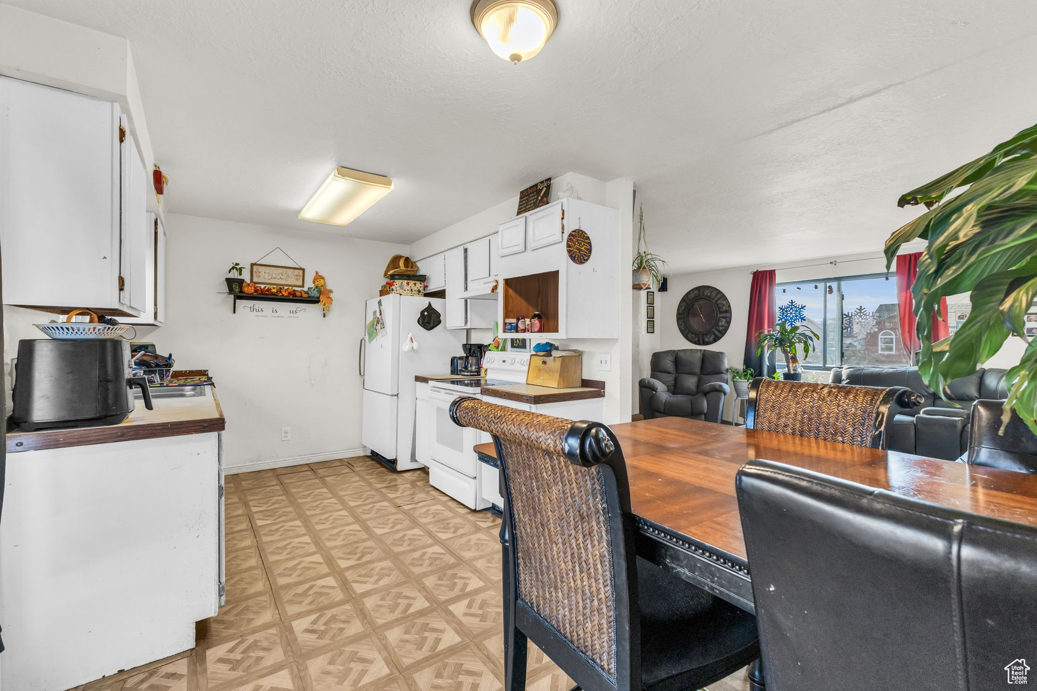 Kitchen featuring a textured ceiling, white cabinetry, and white appliances