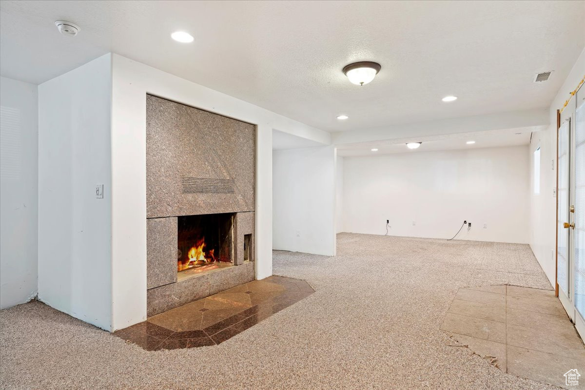 Unfurnished living room with carpet flooring and a large fireplace