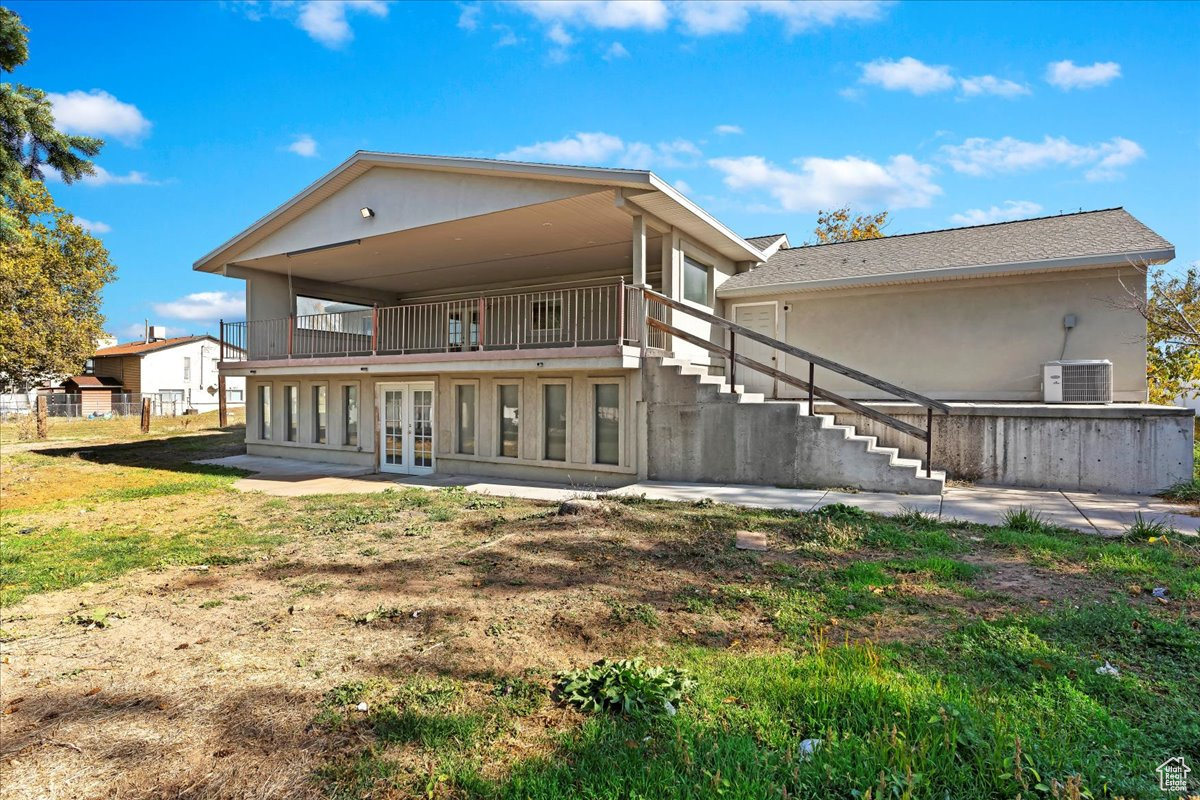 Rear view of property featuring cooling unit, french doors, and a balcony