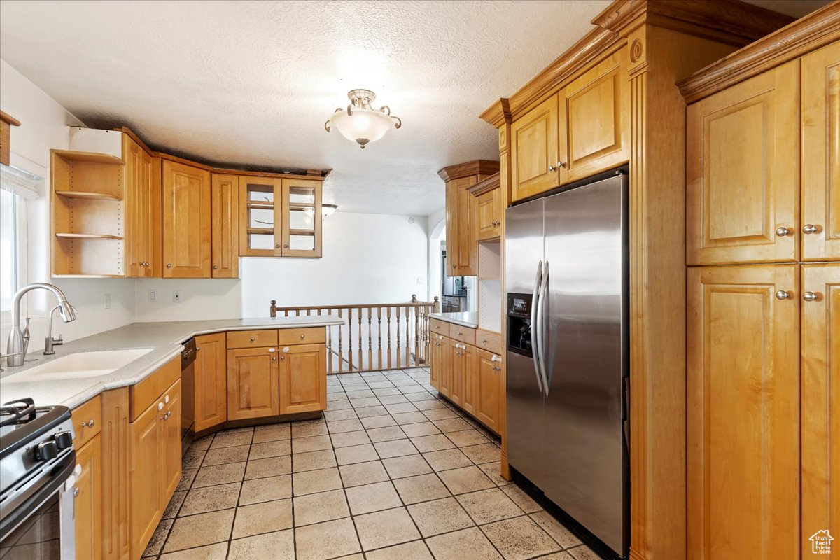 Kitchen with a wealth of natural light, sink, light tile patterned floors, and stainless steel appliances