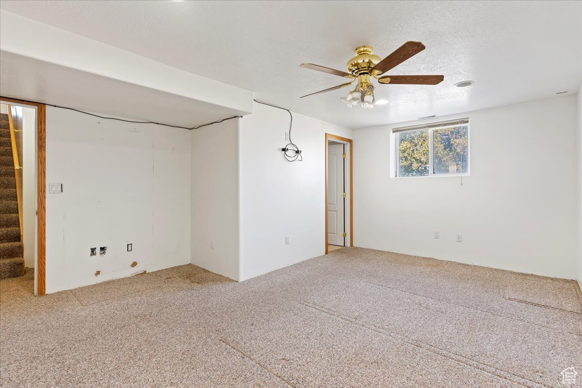 Carpeted spare room featuring ceiling fan