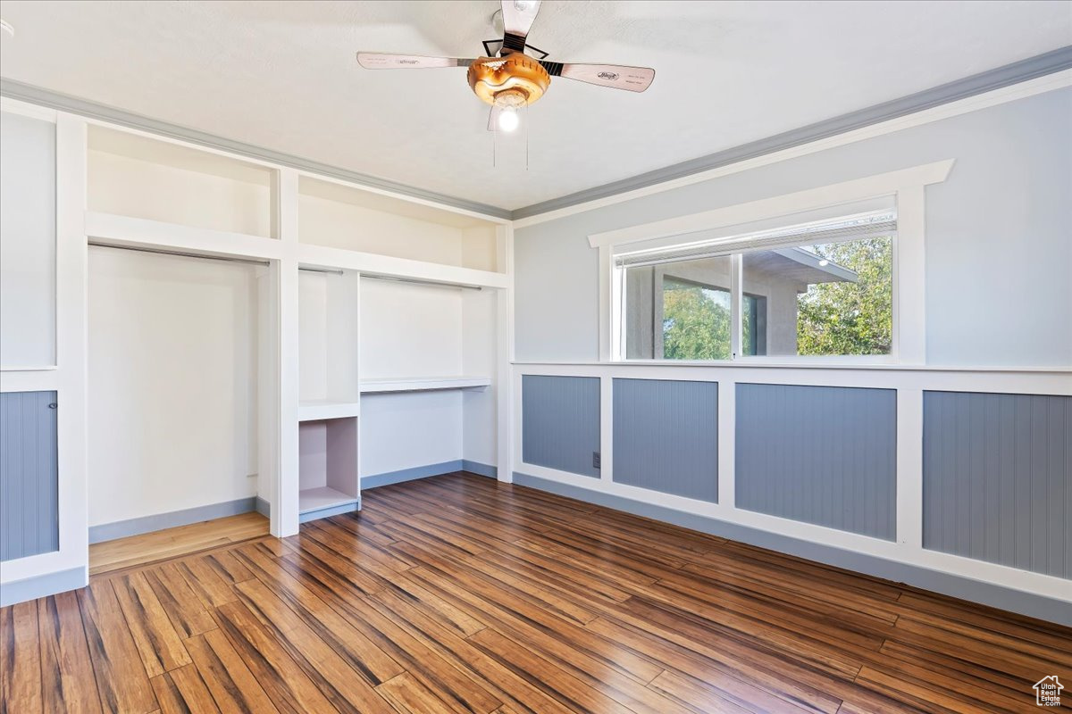 Unfurnished bedroom featuring hardwood / wood-style flooring, ceiling fan, and ornamental molding