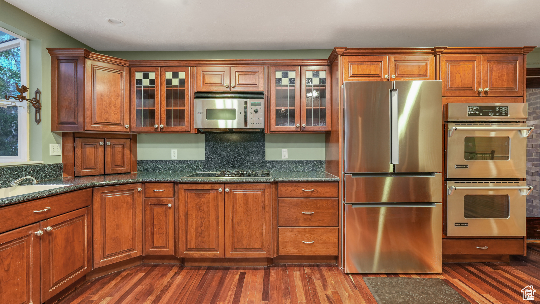 Kitchen with dark hardwood / wood-style floors, sink, backsplash, and appliances with stainless steel finishes