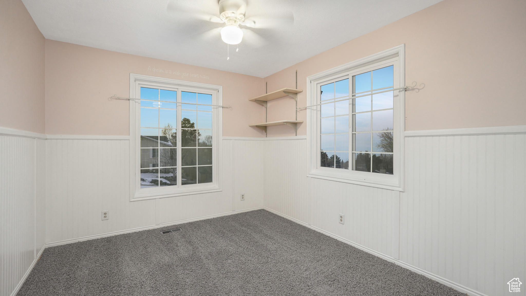 Spare room with ceiling fan and dark colored carpet