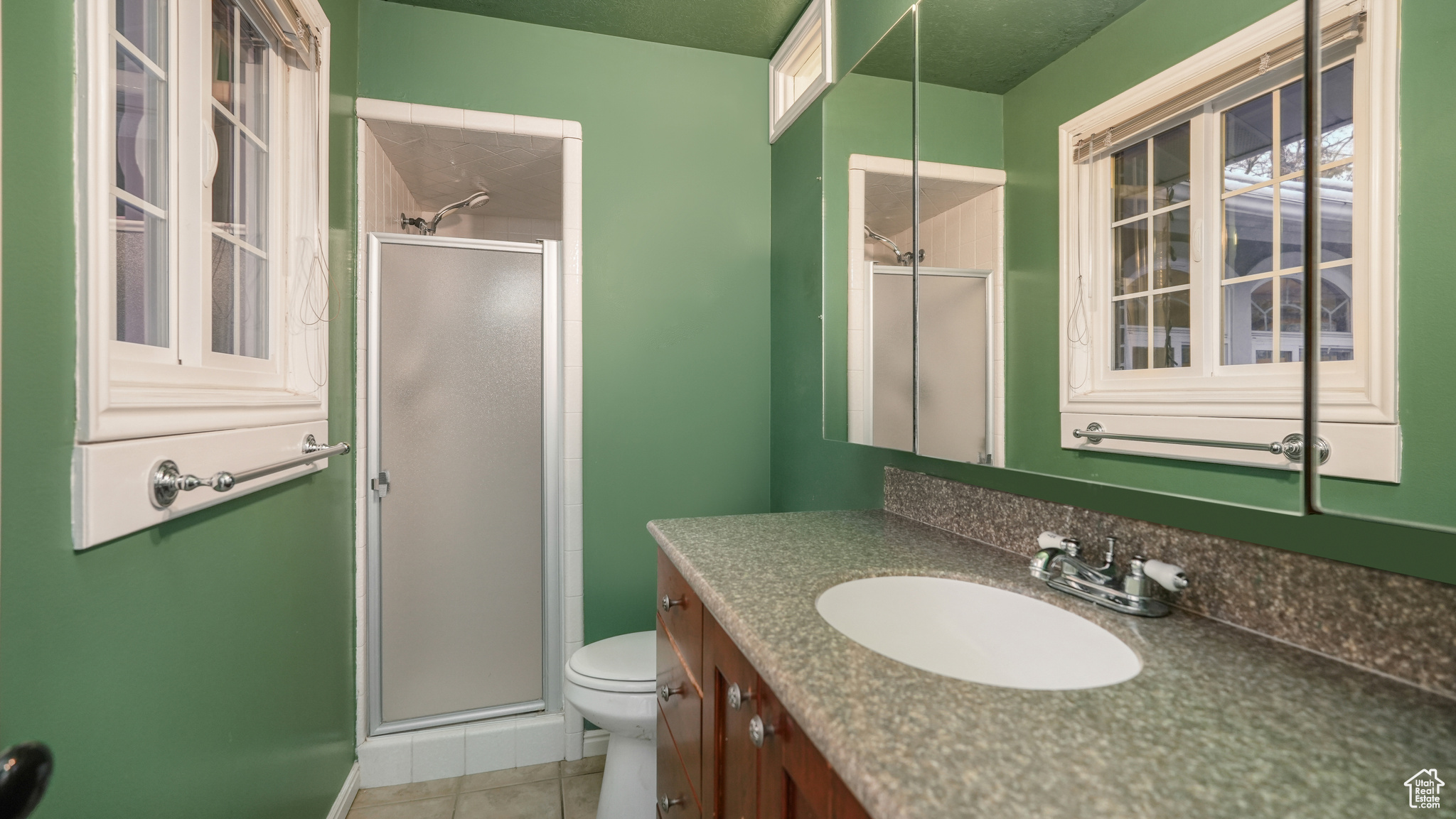 Bathroom featuring tile patterned flooring, vanity, toilet, and a shower with shower door