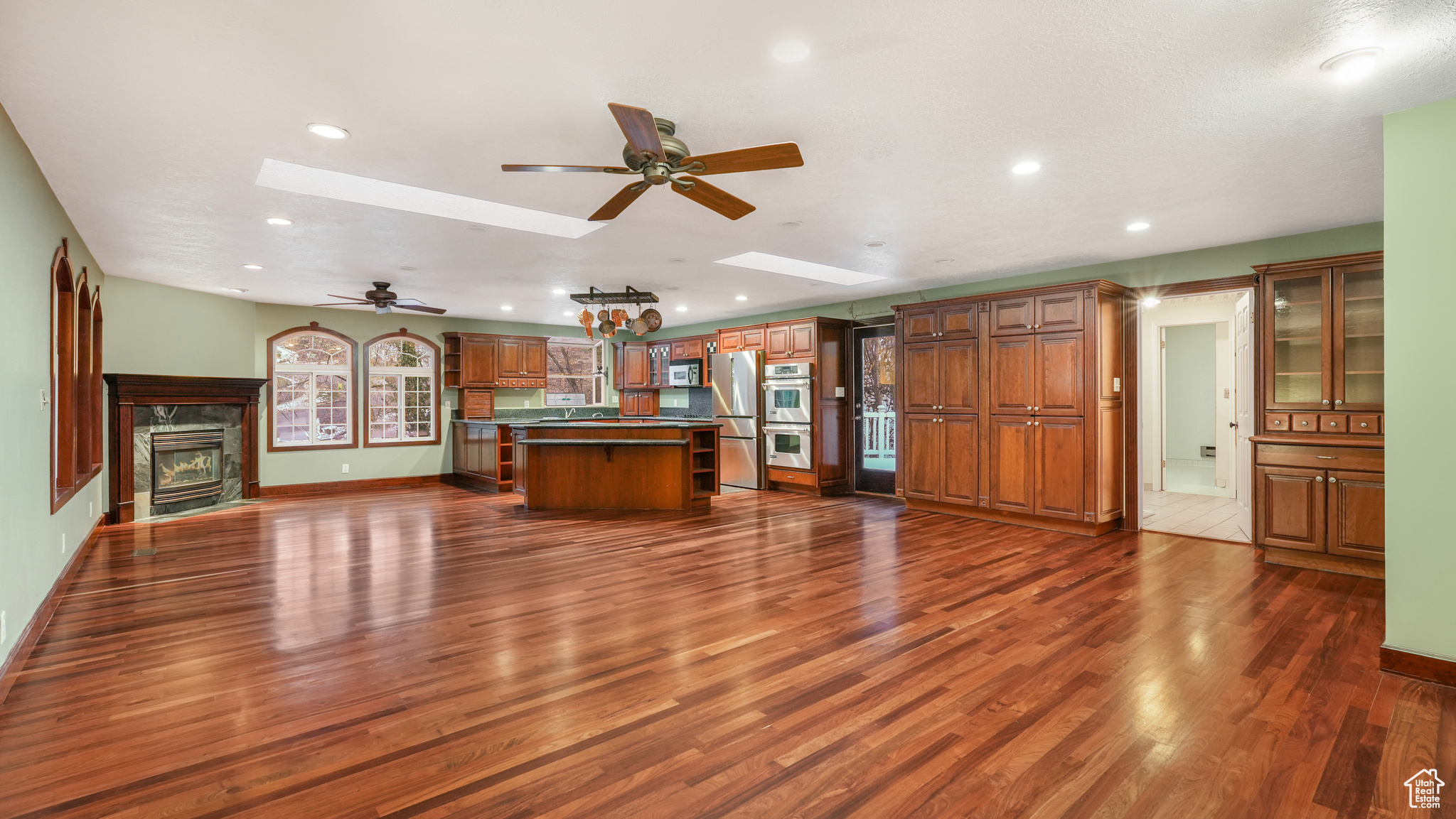 Kitchen with a kitchen island, dark wood-type flooring, appliances with stainless steel finishes, and a skylight