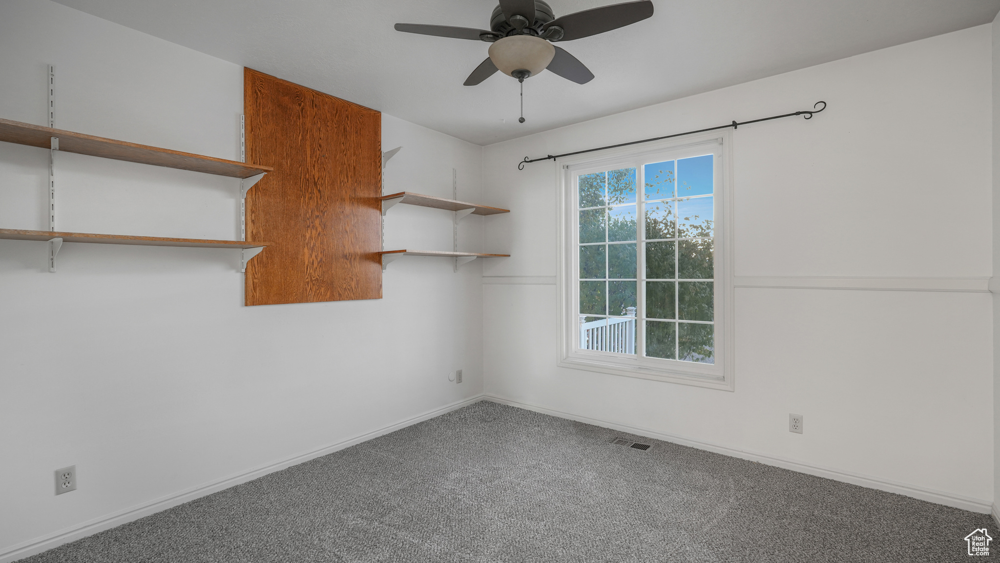 Carpeted spare room featuring ceiling fan