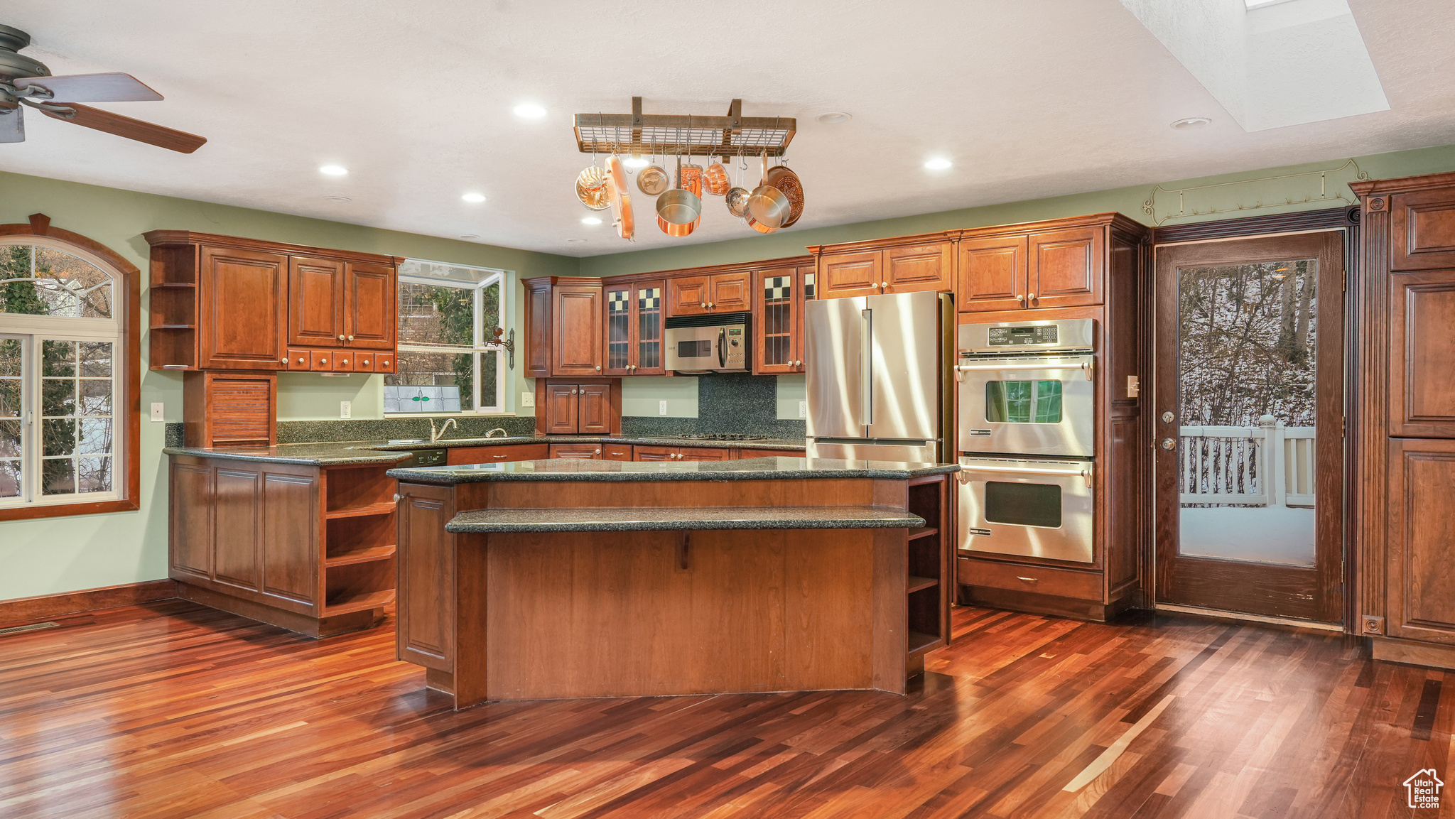 Kitchen featuring a skylight, ceiling fan, a kitchen island, dark hardwood / wood-style flooring, and stainless steel appliances