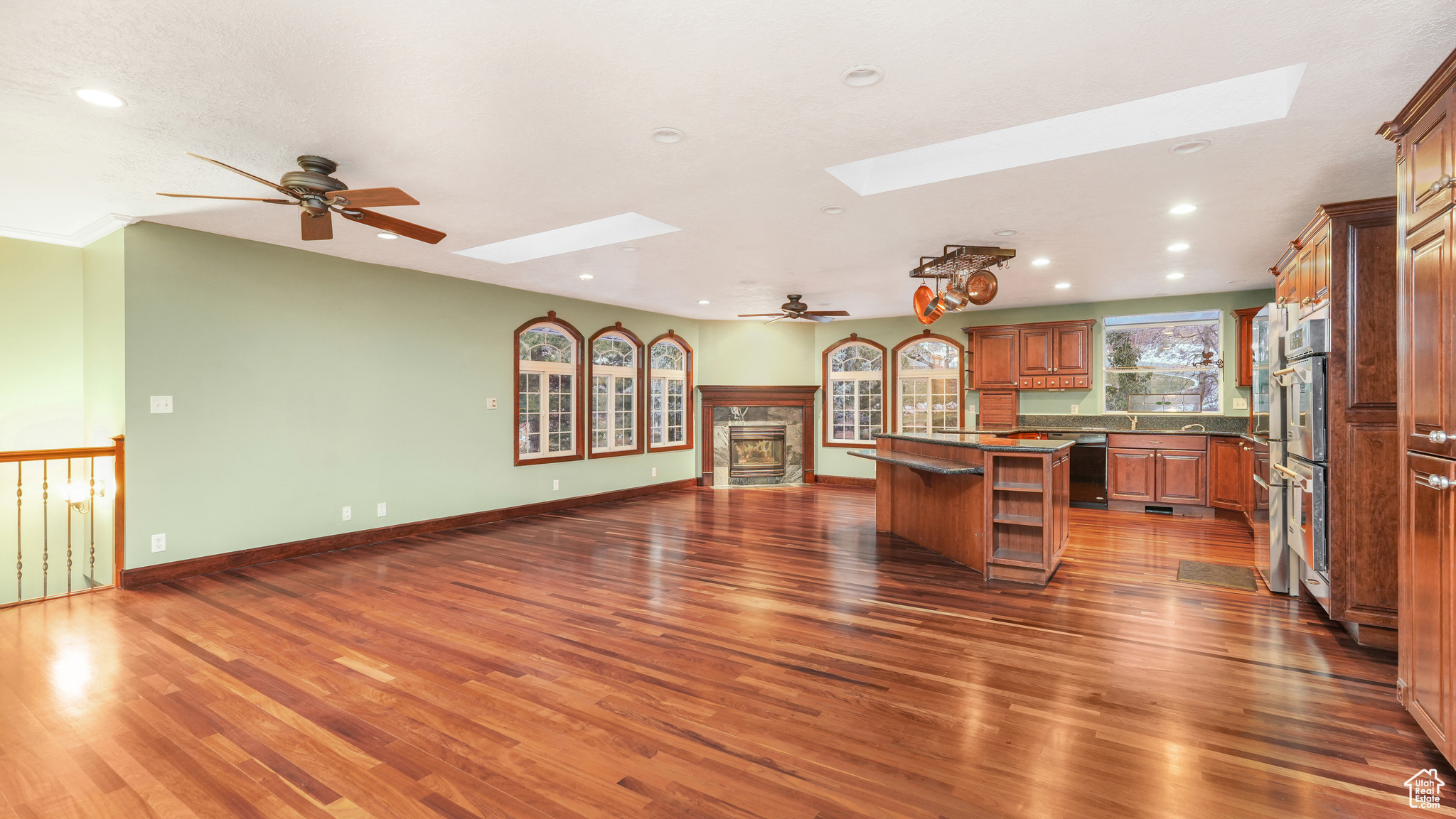 Kitchen with a skylight, ceiling fan, a center island, a kitchen breakfast bar, and dark hardwood / wood-style floors