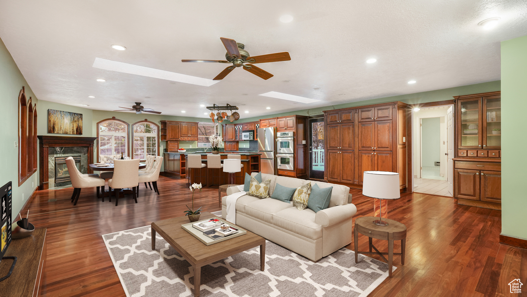 Living room with a skylight, dark hardwood / wood-style floors, and ceiling fan