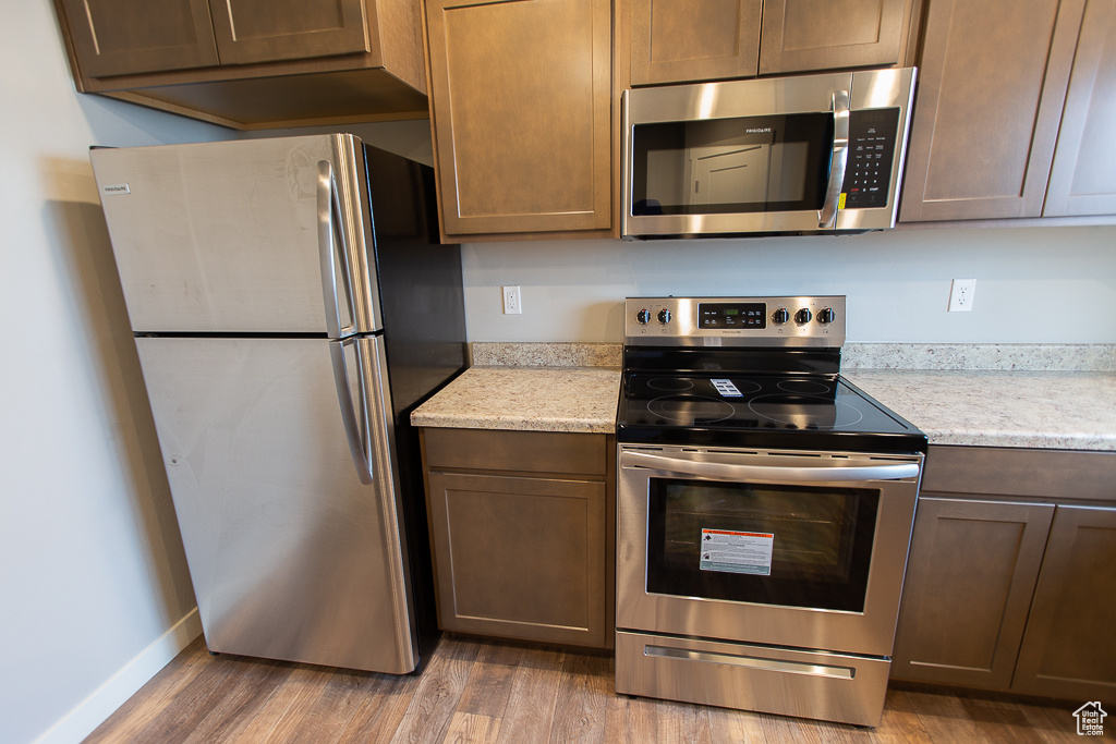 Kitchen featuring light stone countertops, dark wood-type flooring, and appliances with stainless steel finishes