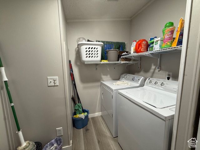 Laundry room with washer and dryer, a textured ceiling, light hardwood / wood-style flooring, and crown molding