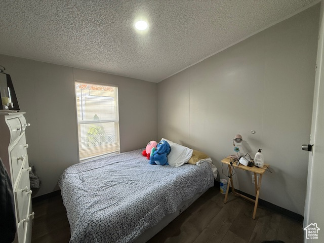 Bedroom with a textured ceiling and dark hardwood / wood-style floors