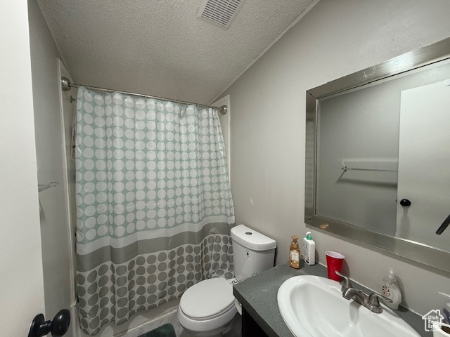 Bathroom featuring a shower with shower curtain, vanity, toilet, and a textured ceiling