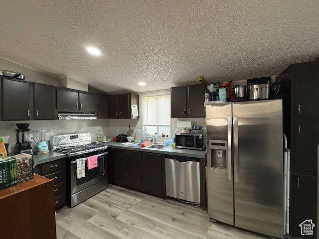 Kitchen featuring appliances with stainless steel finishes, dark brown cabinets, a textured ceiling, sink, and light hardwood / wood-style floors