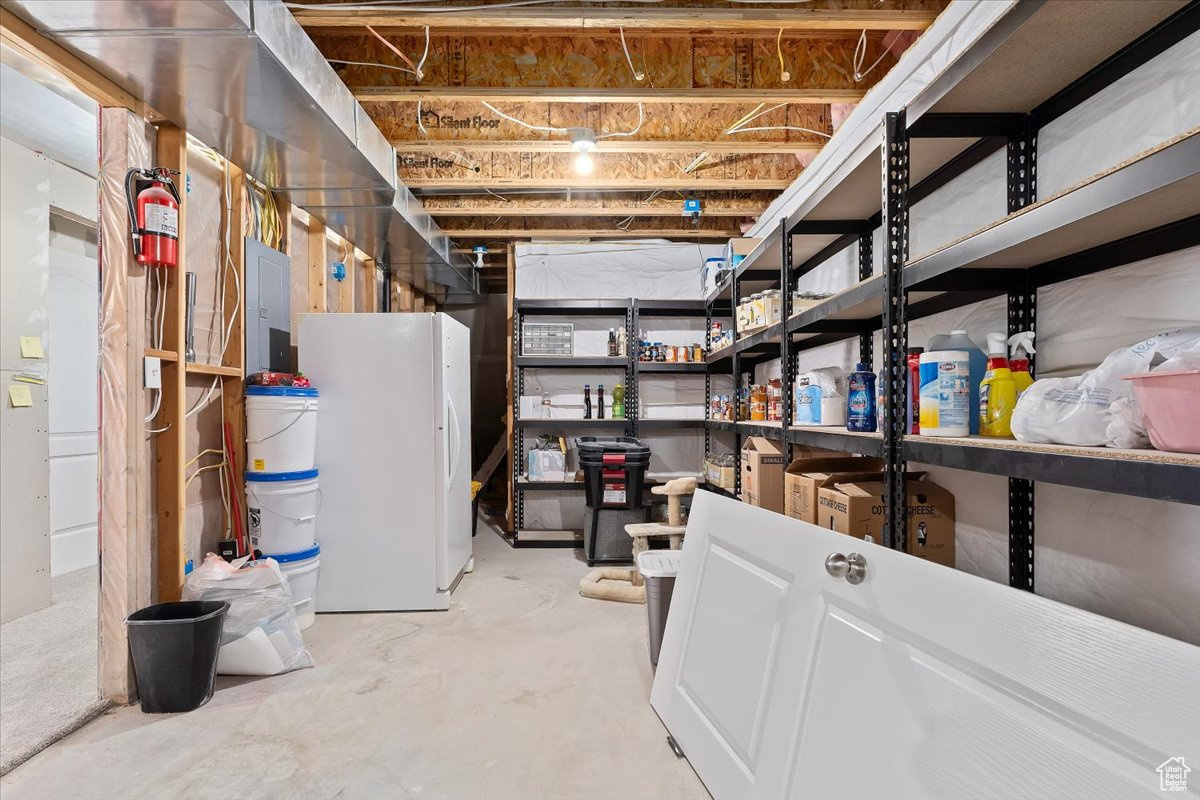 Basement with electric panel and white freezer (included)