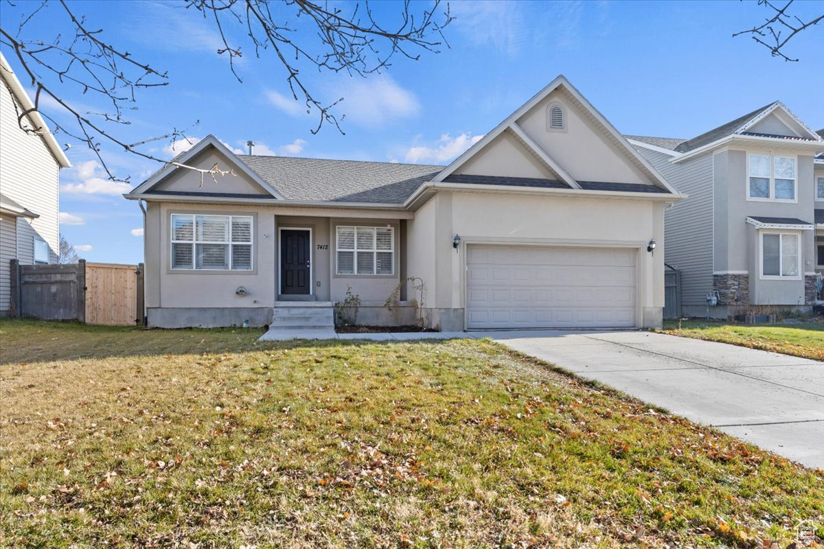 Single story home with a garage and a front lawn