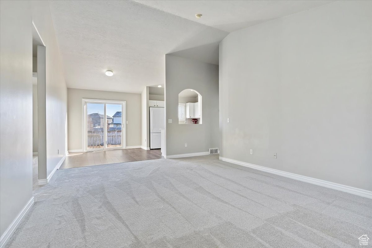 Unfurnished room featuring carpet flooring and lofted ceiling