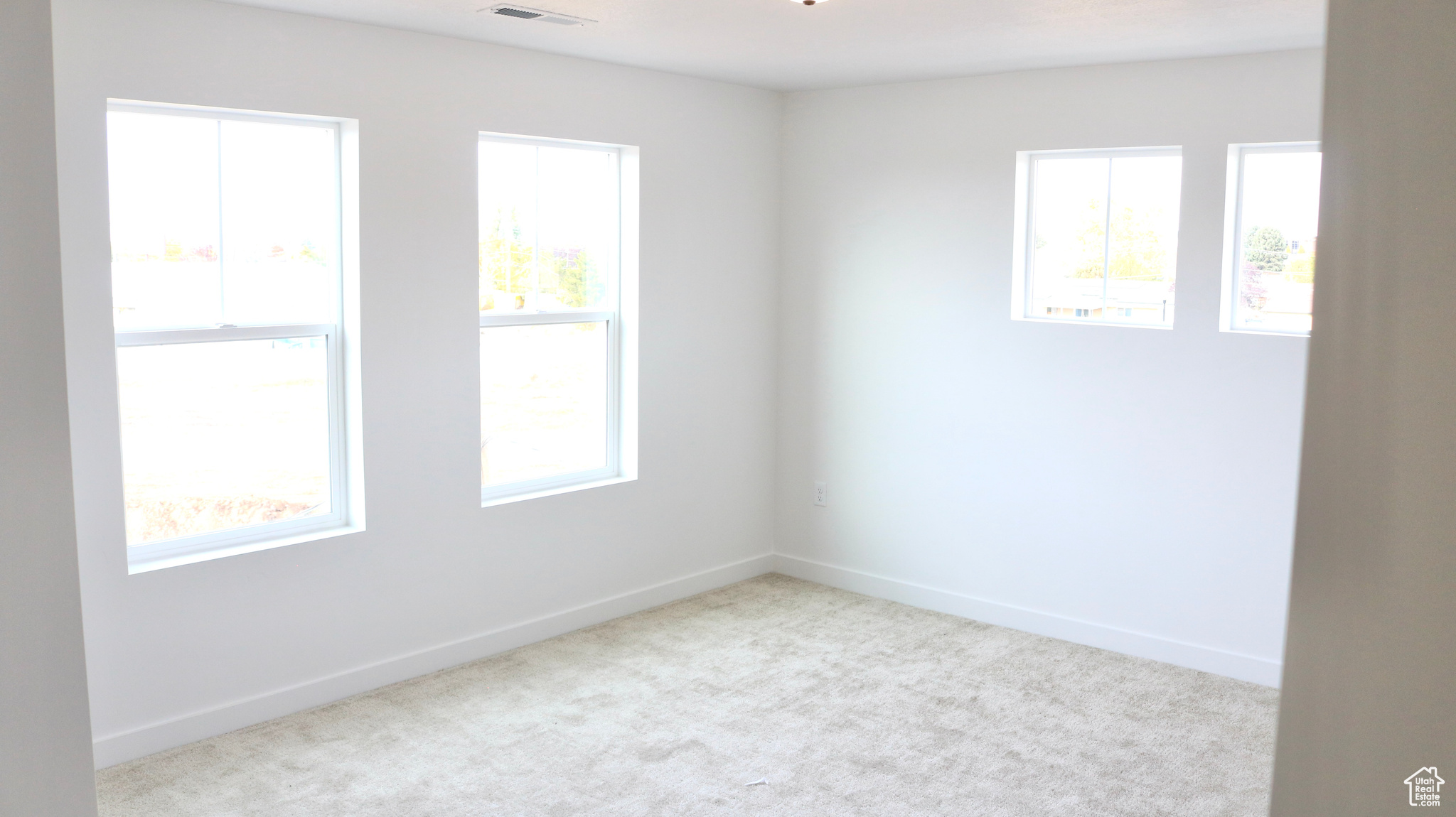 Spare room featuring light carpet and a wealth of natural light