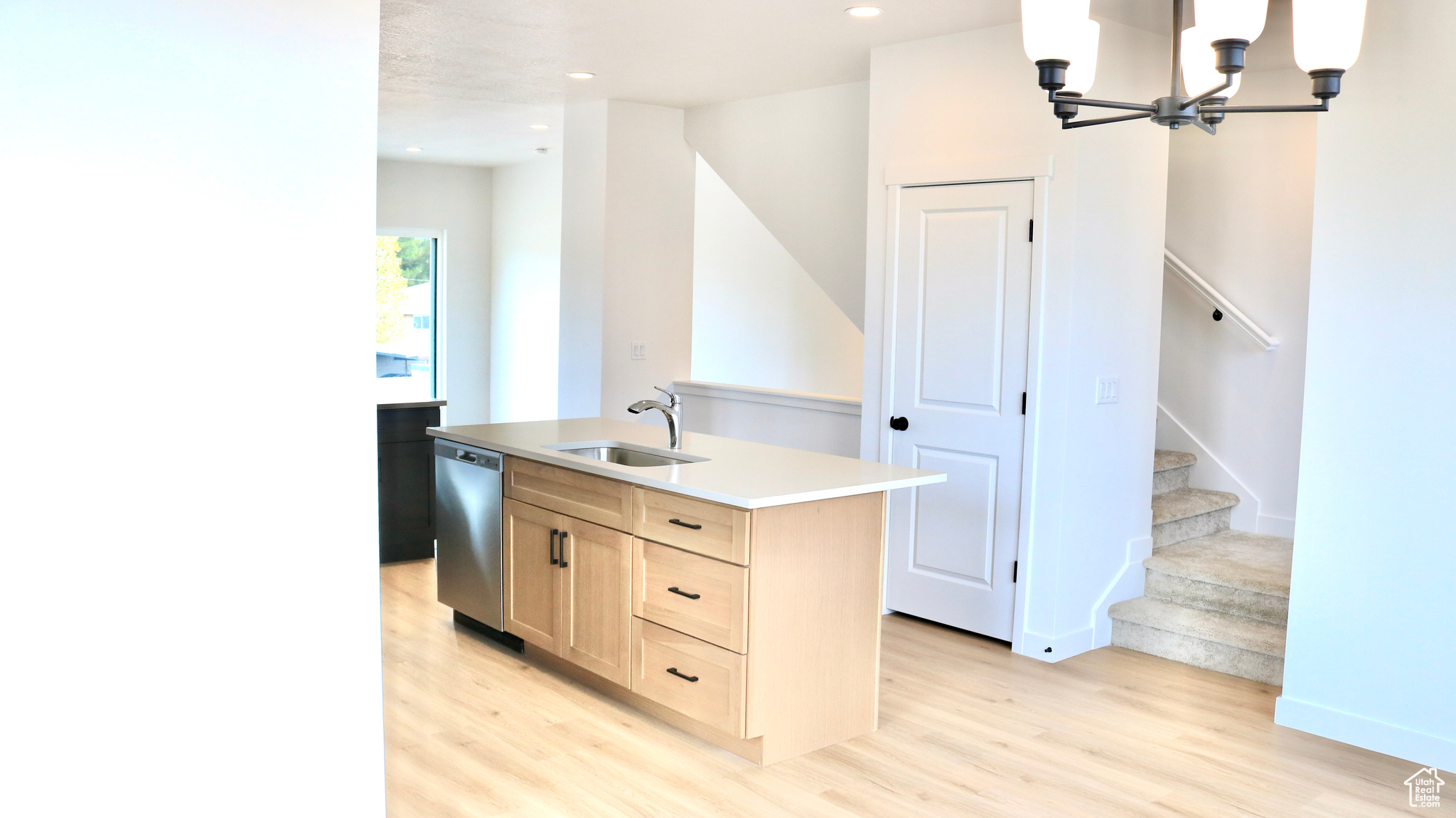 Kitchen featuring a center island with sink, dishwasher, sink, and light hardwood / wood-style flooring