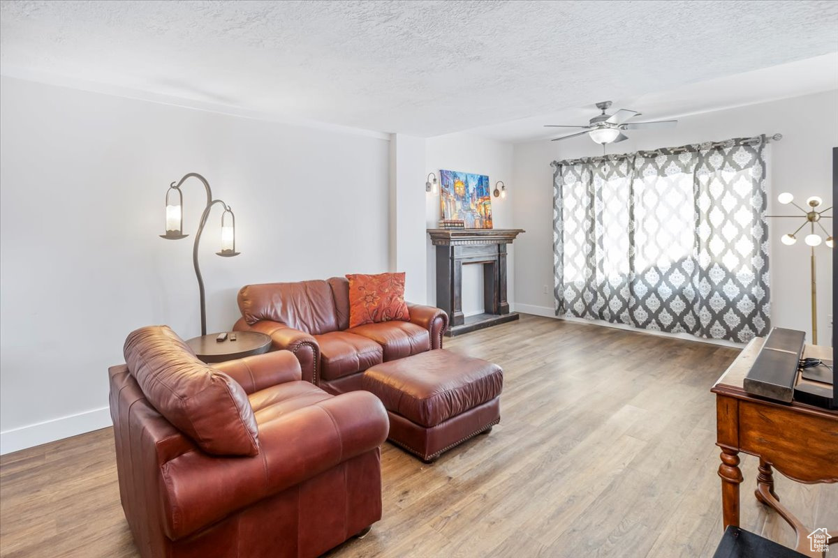 Living room featuring ceiling fan, hardwood / wood-style floors, and a textured ceiling