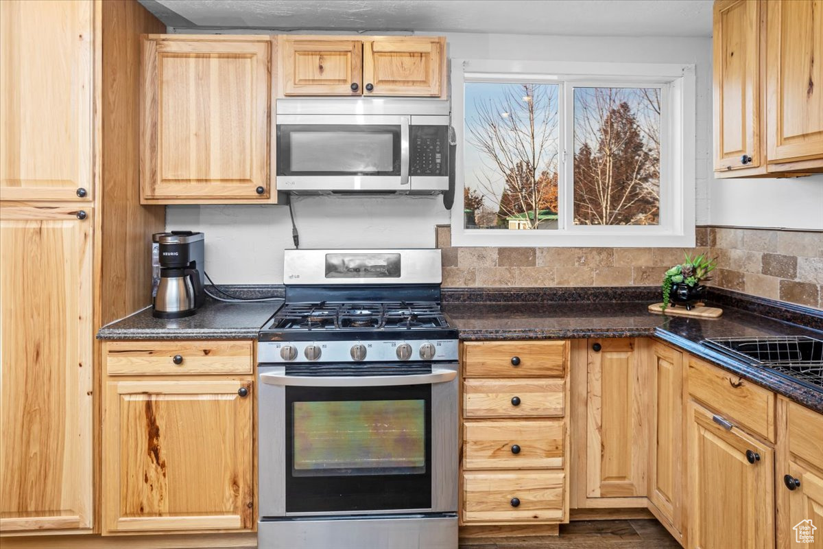 Kitchen featuring backsplash, light brown cabinetry, and appliances with stainless steel finishes