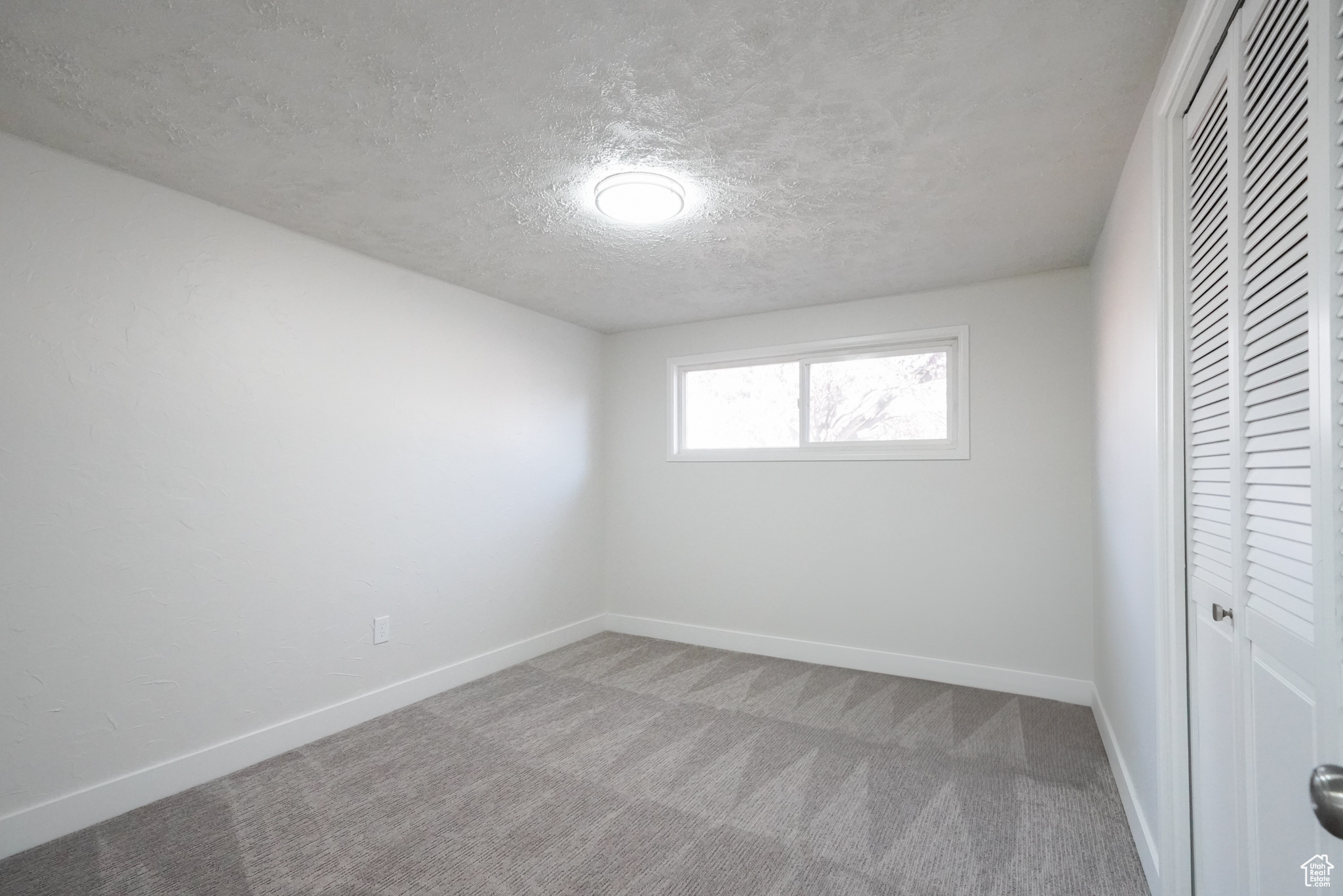 Unfurnished bedroom with a textured ceiling and carpet floors