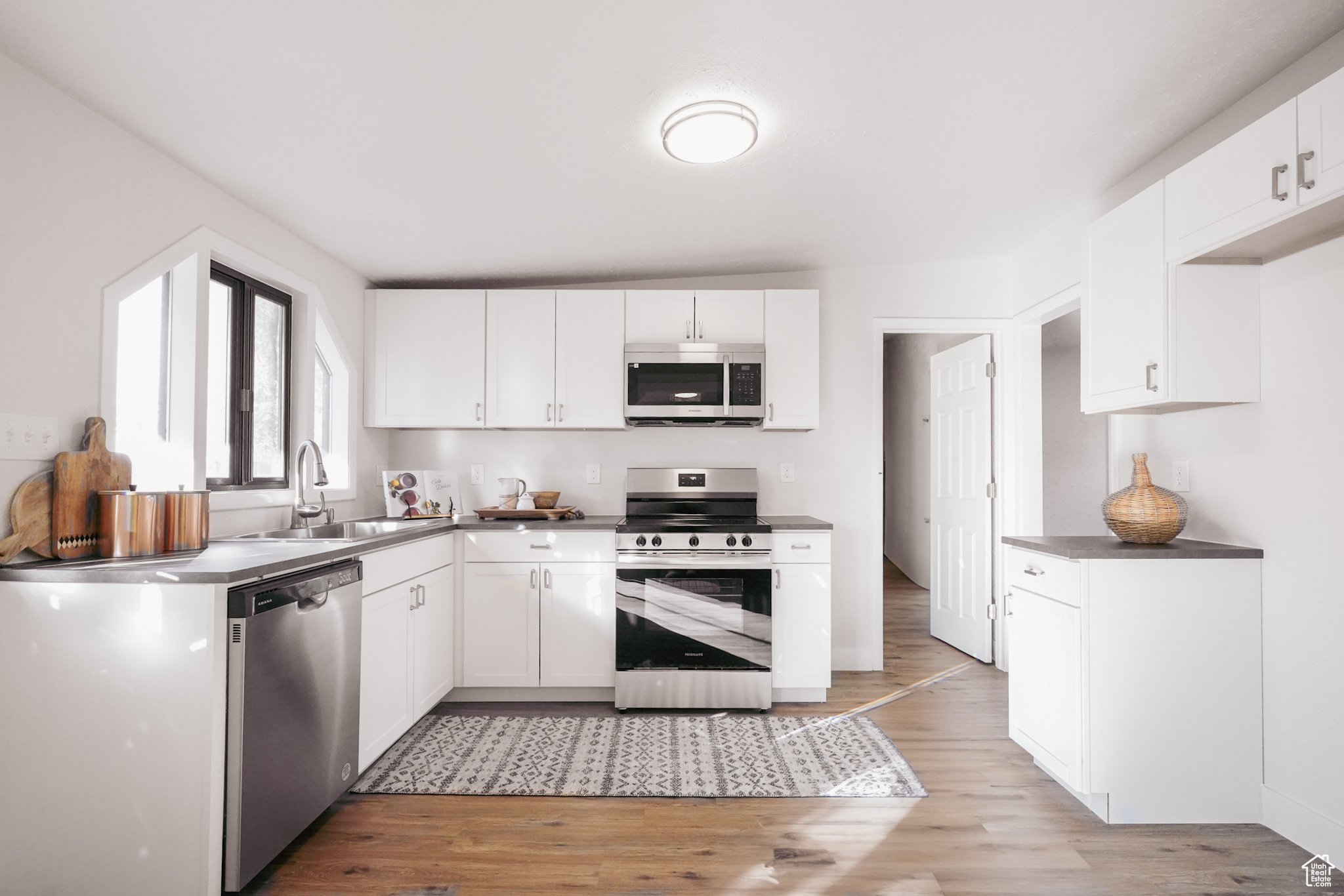 Kitchen featuring white cabinets, stainless steel appliances, light hardwood / wood-style flooring, and sink