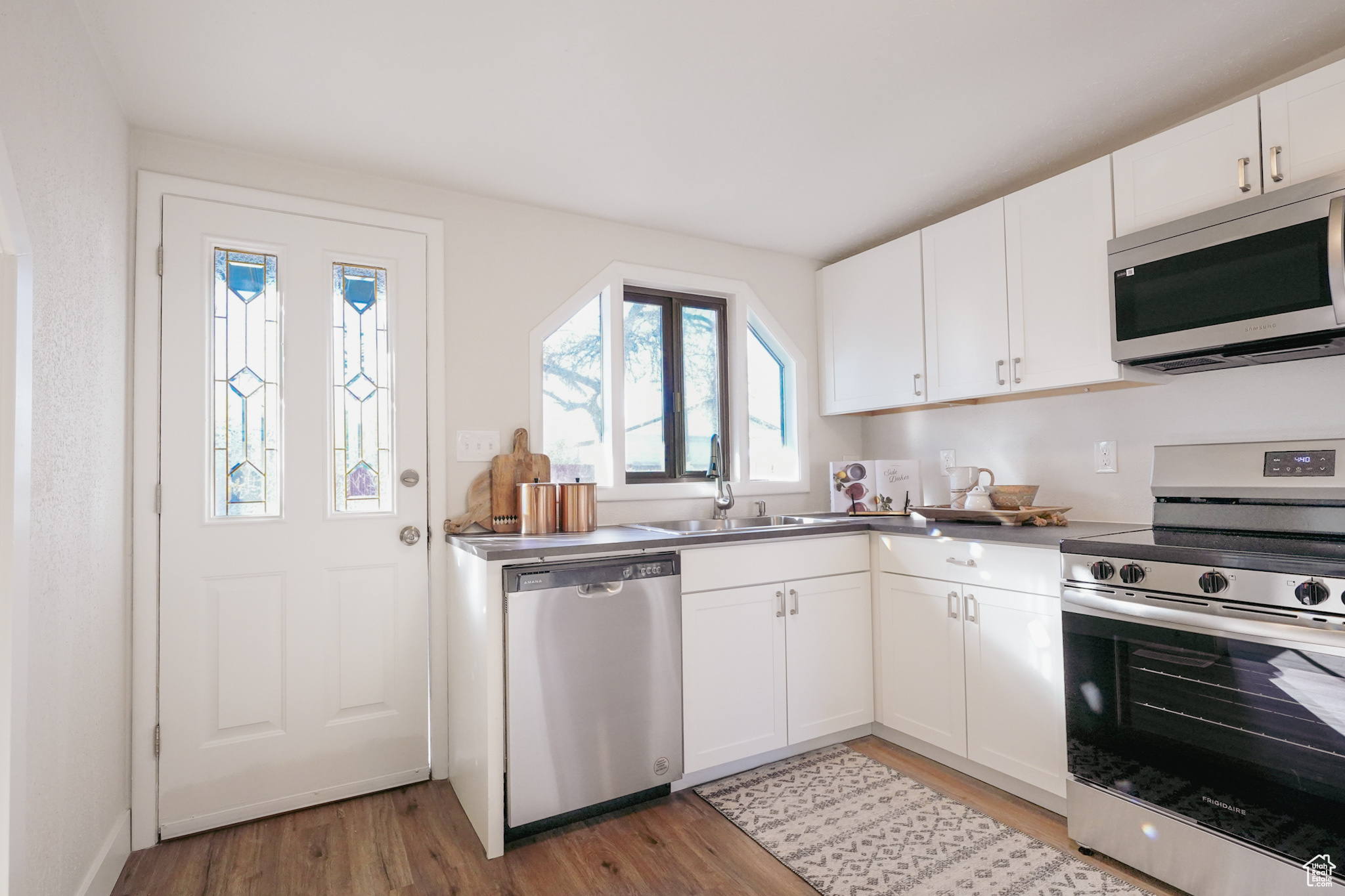 Kitchen featuring white cabinets, sink, stainless steel appliances, and light hardwood / wood-style flooring