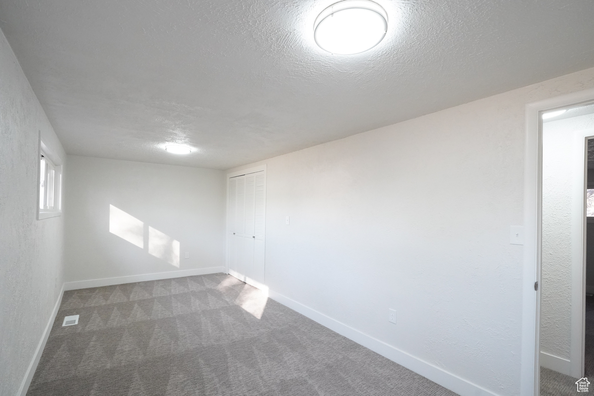 Carpeted empty room featuring a textured ceiling