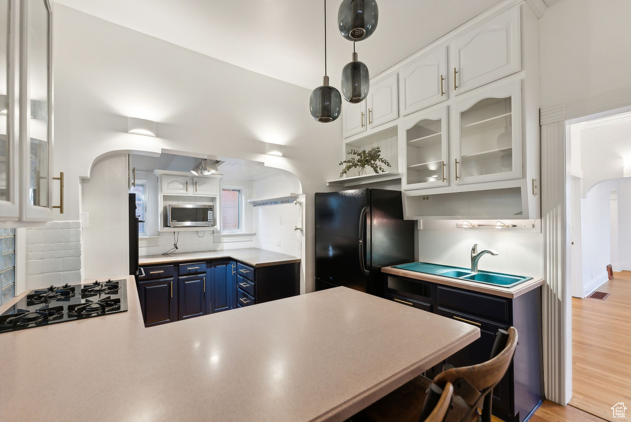 Kitchen featuring white cabinets, stainless steel appliances, blue cabinets, and light hardwood / wood-style floors