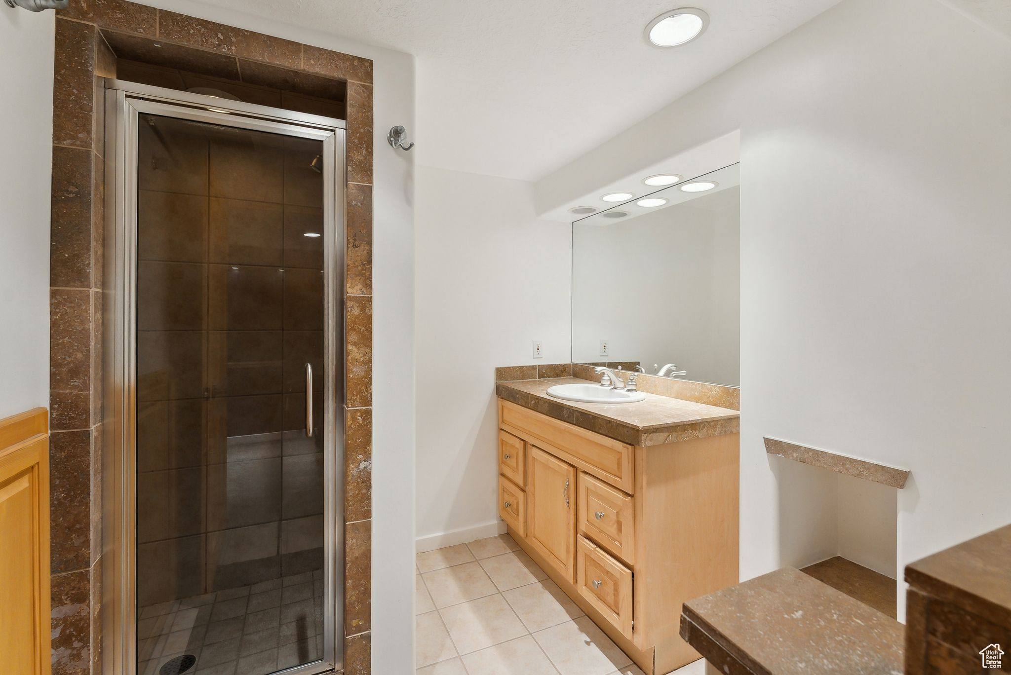 Bathroom featuring tile patterned floors, vanity, and a shower with shower door