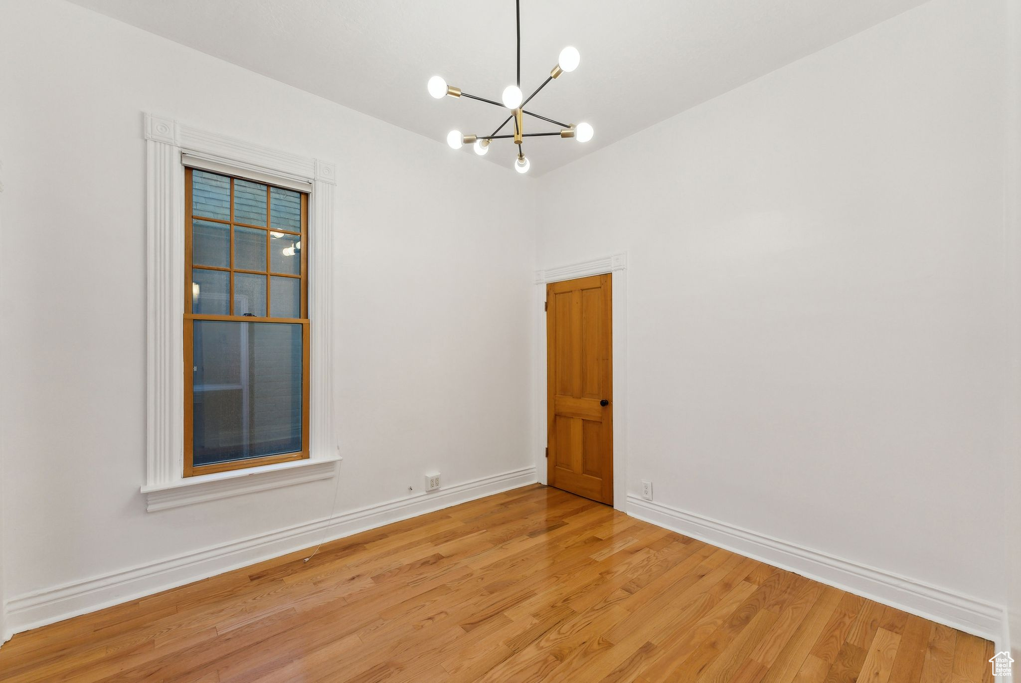 Unfurnished room with wood-type flooring and a notable chandelier