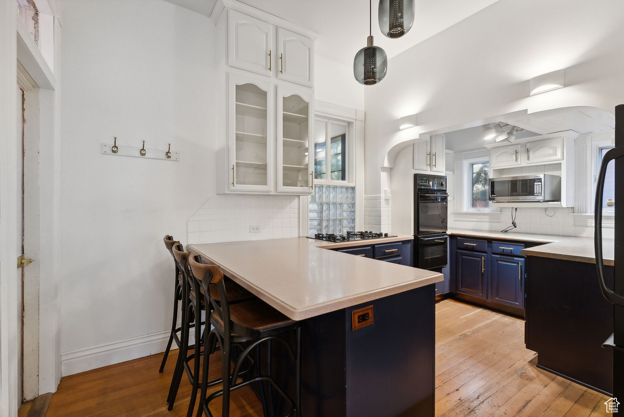 Kitchen featuring tasteful backsplash, blue cabinets, a breakfast bar, white cabinets, and light wood-type flooring