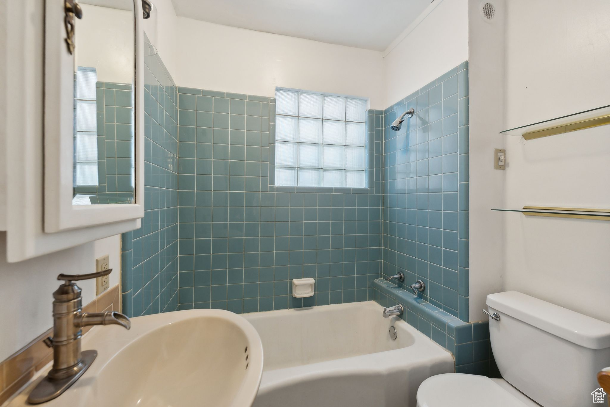 Full bathroom with tiled shower / bath combo, toilet, sink, and natural light