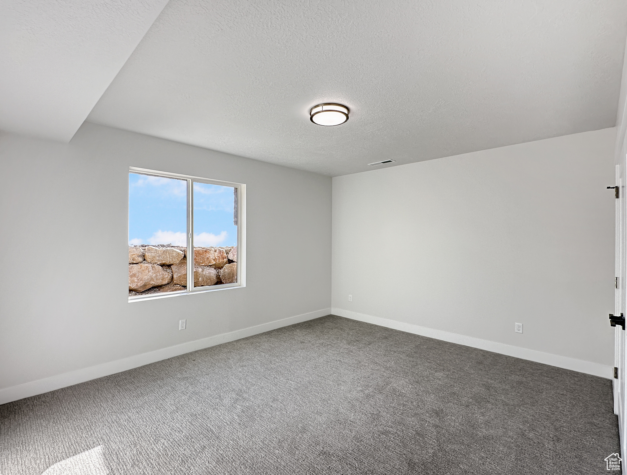 Empty room with carpet and a textured ceiling