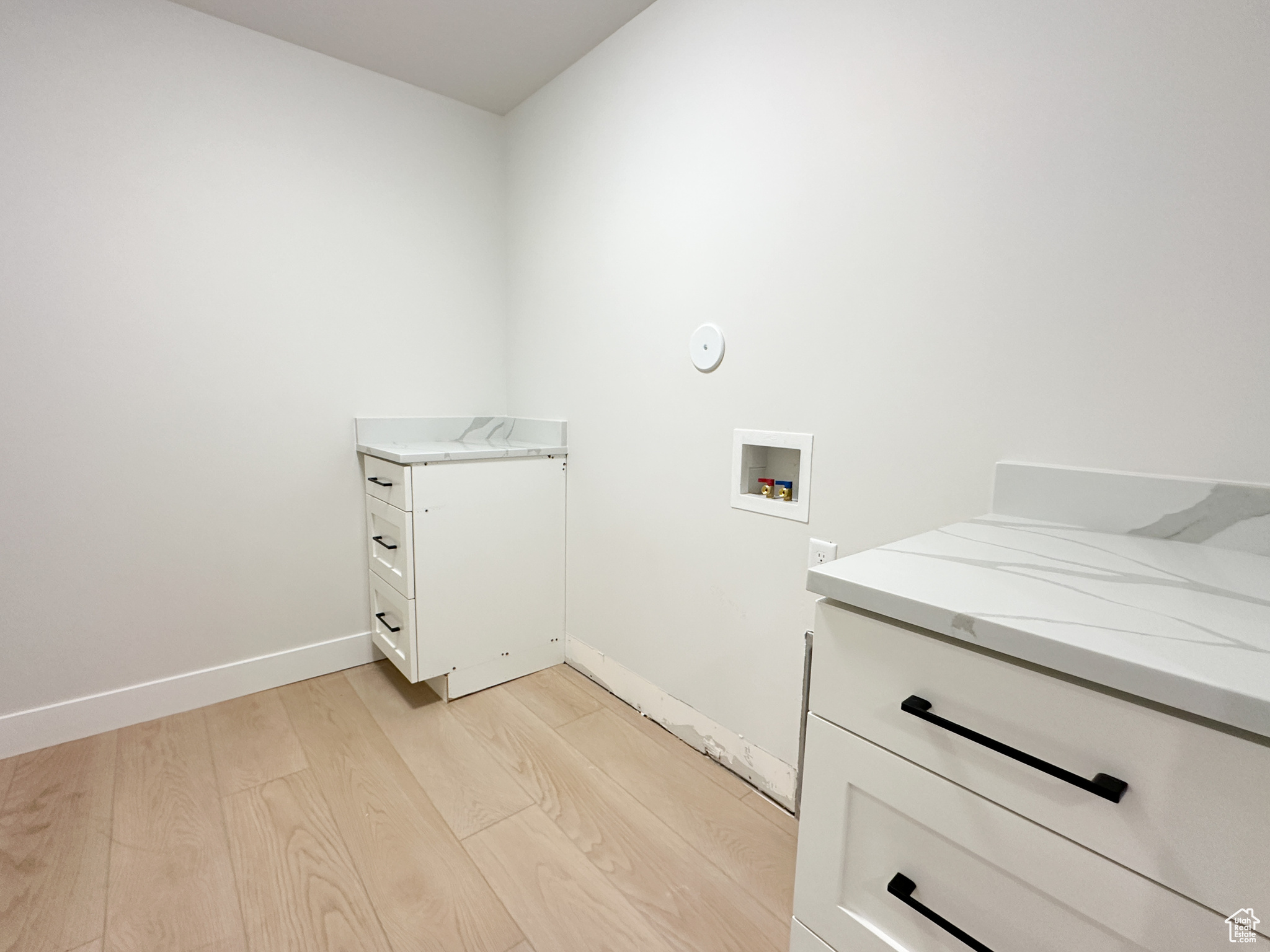 Laundry area with cabinets, light wood-type flooring, and hookup for a washing machine