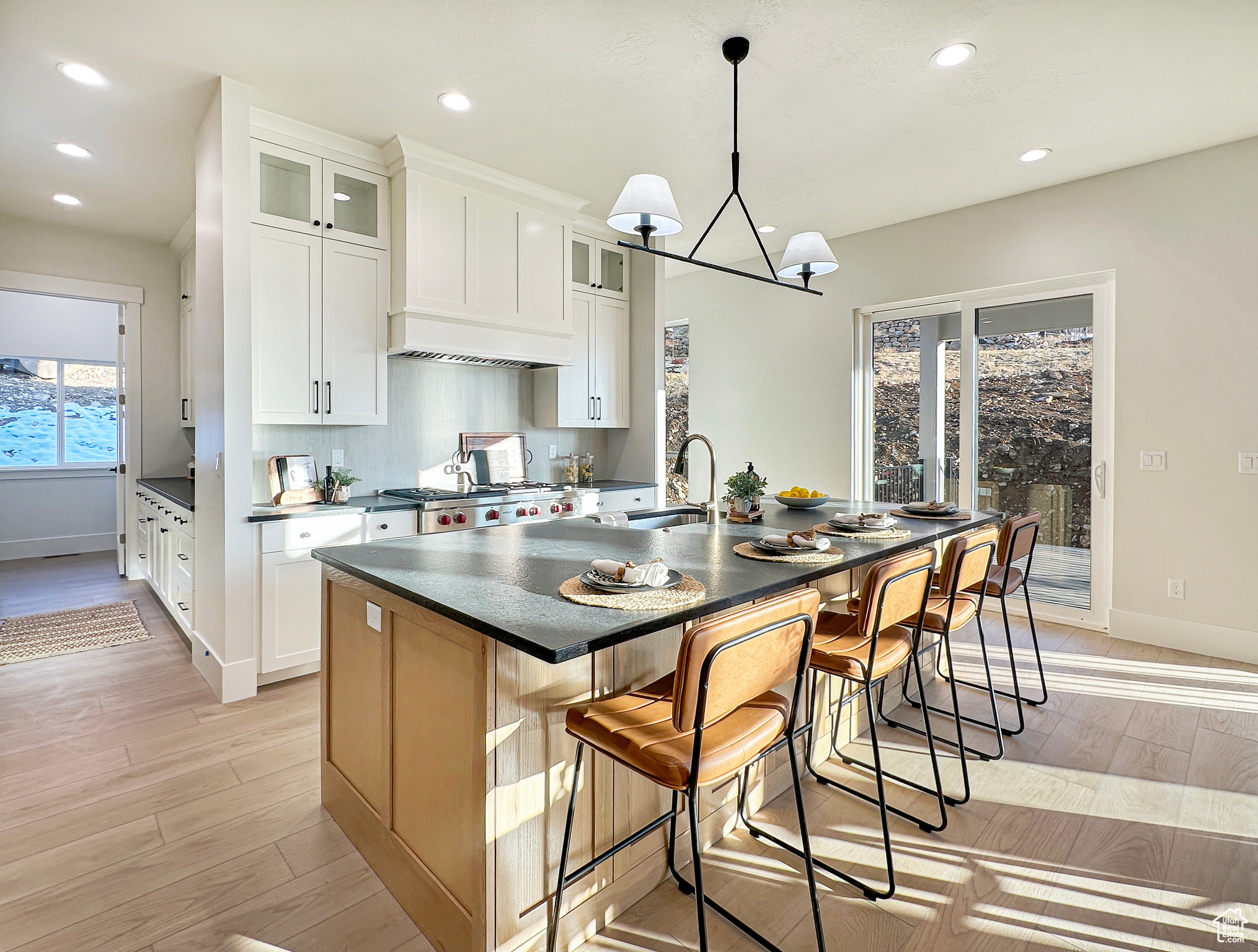 Kitchen with a breakfast bar, a kitchen island with sink, white cabinets, sink, and light hardwood / wood-style flooring