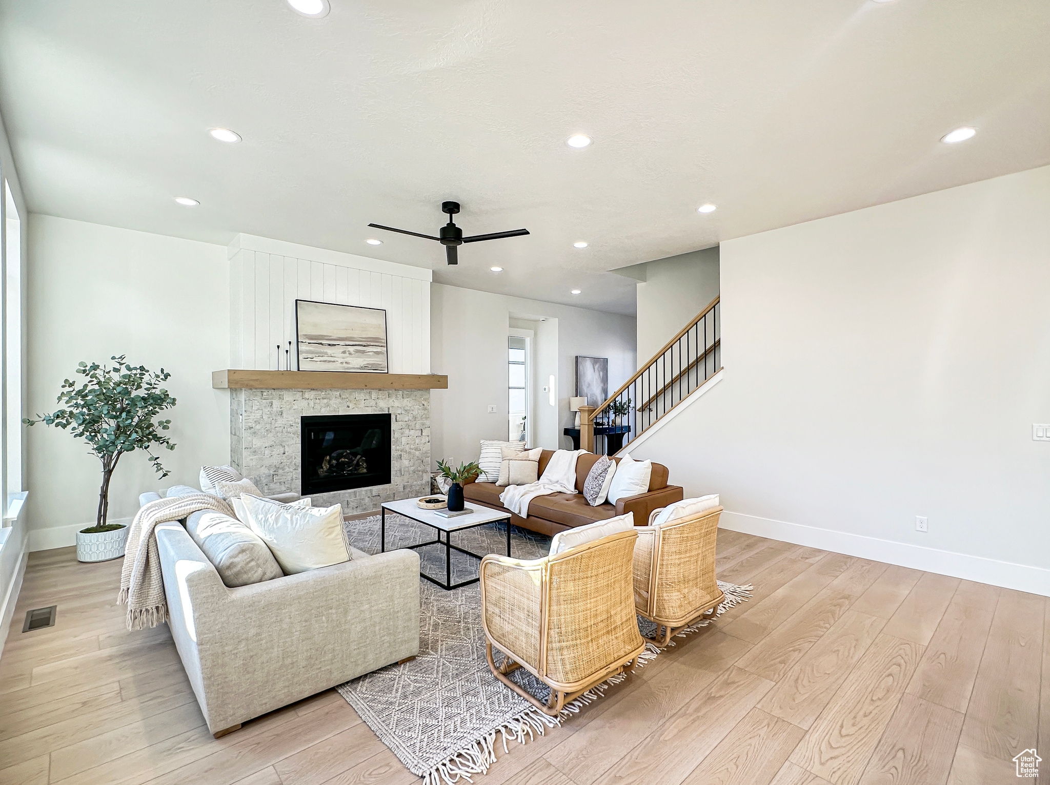 Living room featuring ceiling fan, a fireplace, and light hardwood / wood-style flooring