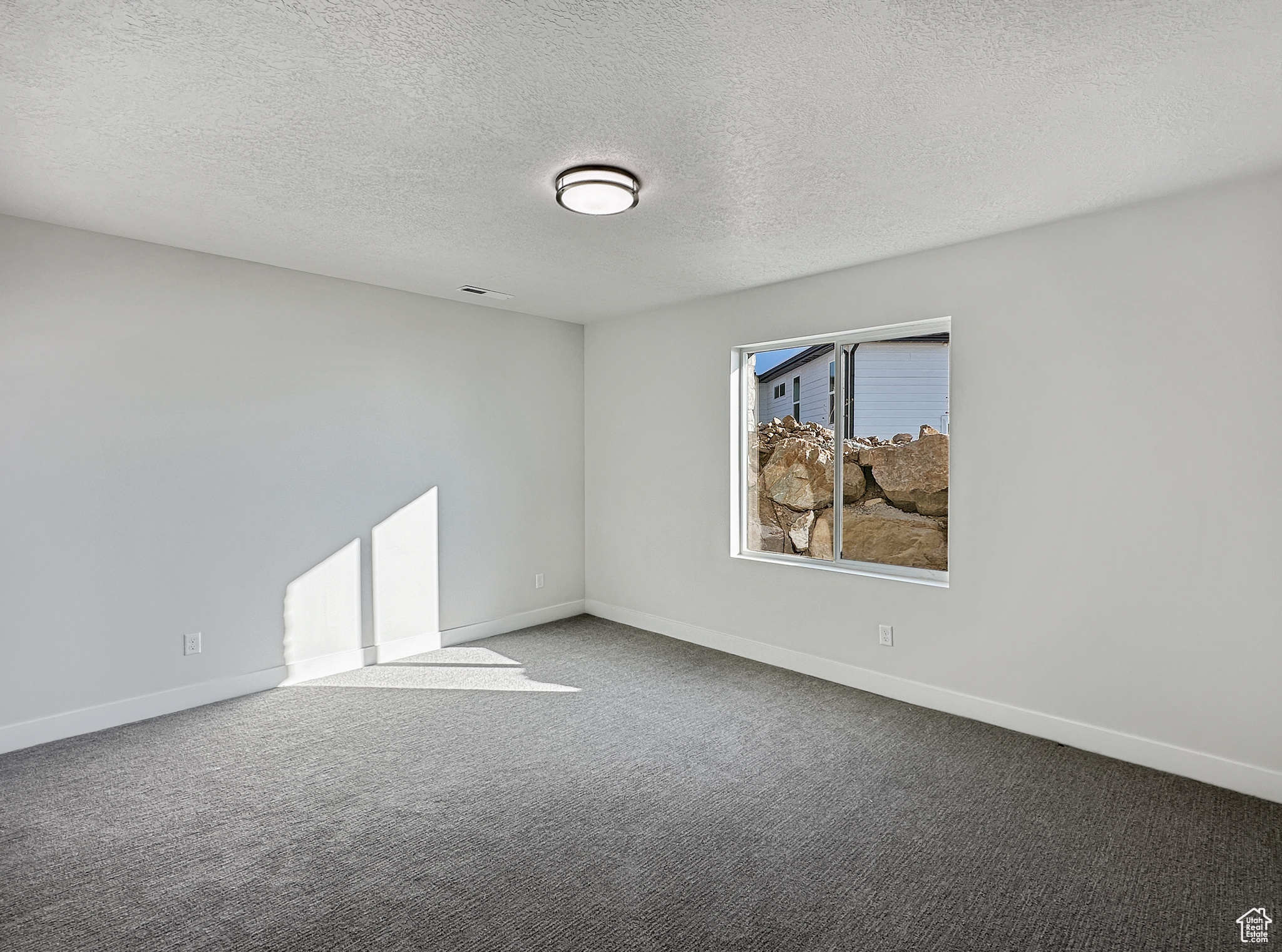 Unfurnished room featuring carpet and a textured ceiling