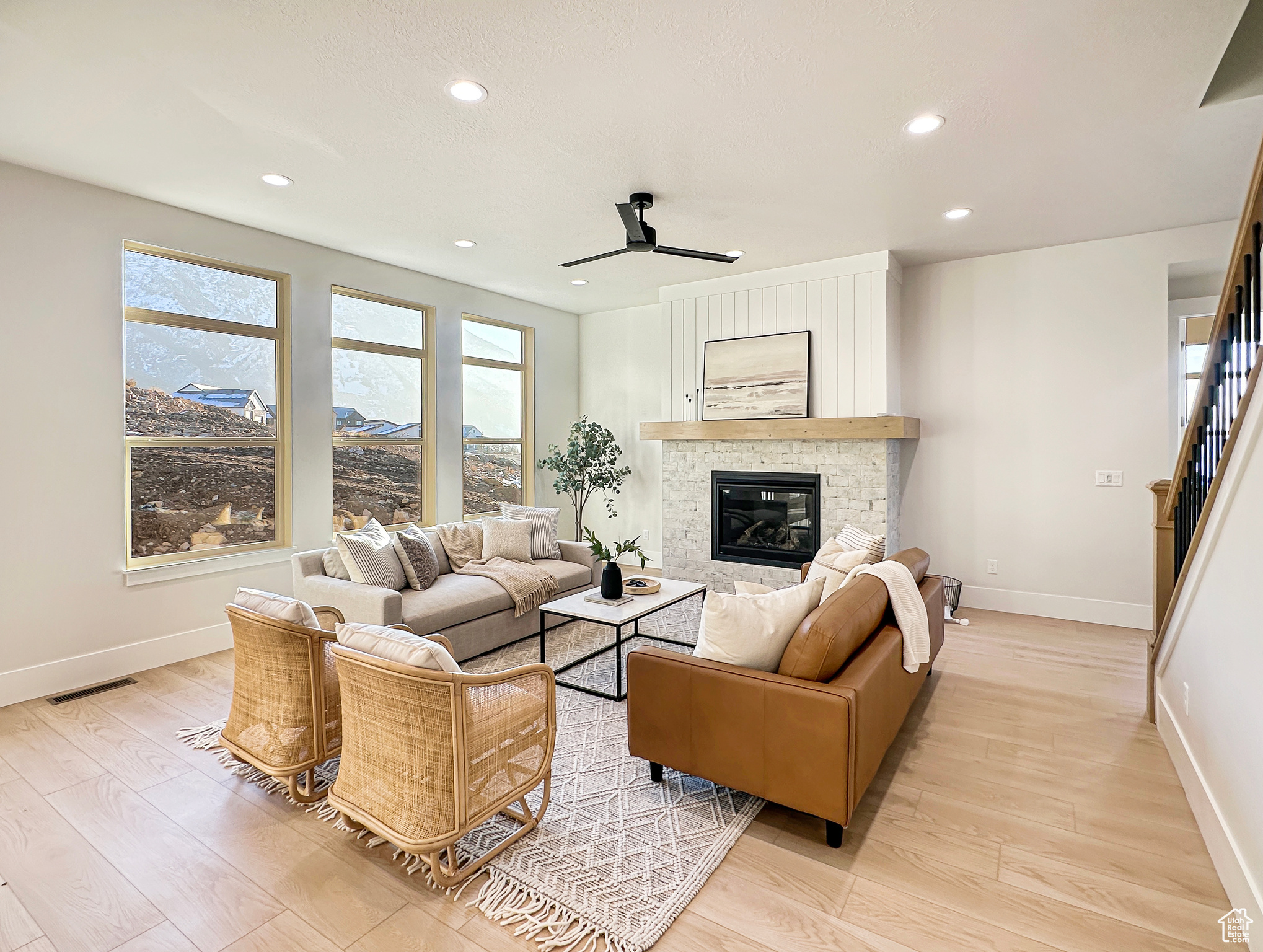 Living room with a fireplace, light hardwood / wood-style flooring, and ceiling fan