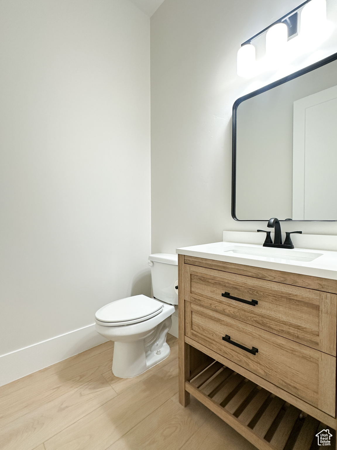 Bathroom featuring hardwood / wood-style floors, vanity, and toilet