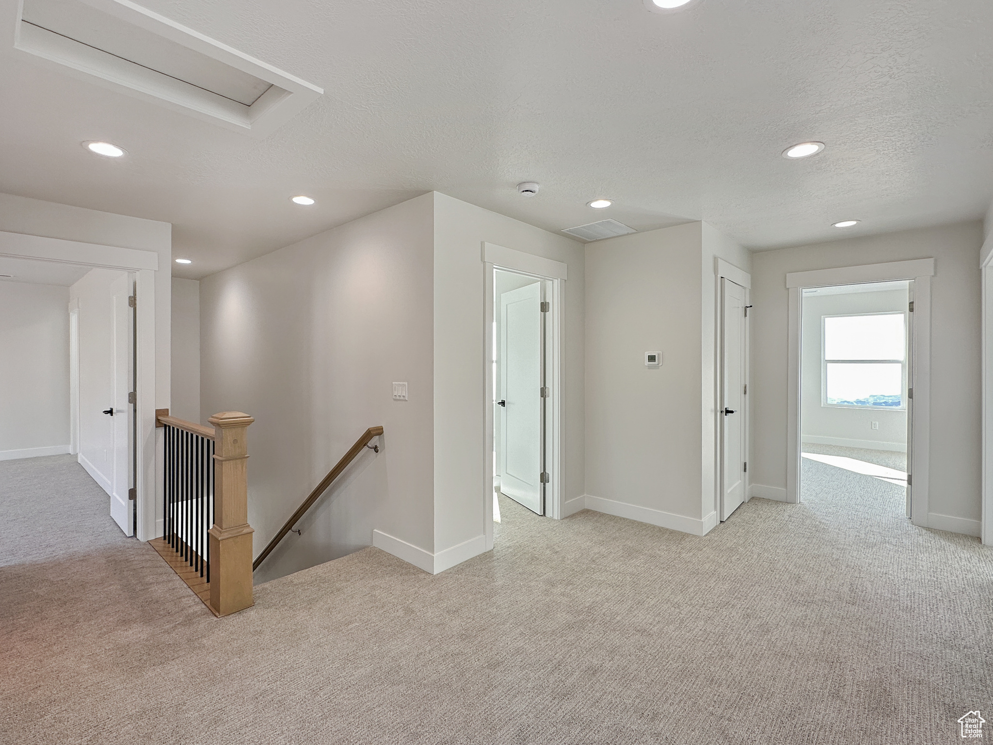 Corridor with light colored carpet and a textured ceiling