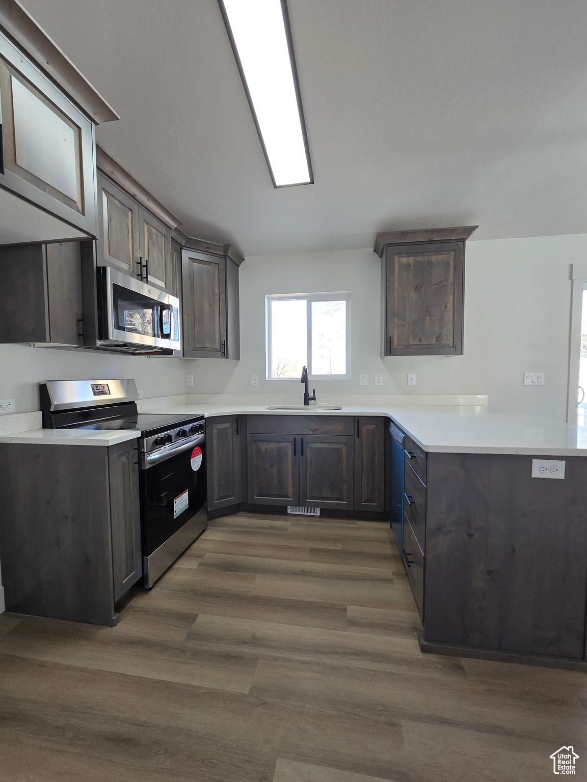 Kitchen featuring dark hardwood / wood-style flooring, dark brown cabinetry, sink, and appliances with stainless steel finishes